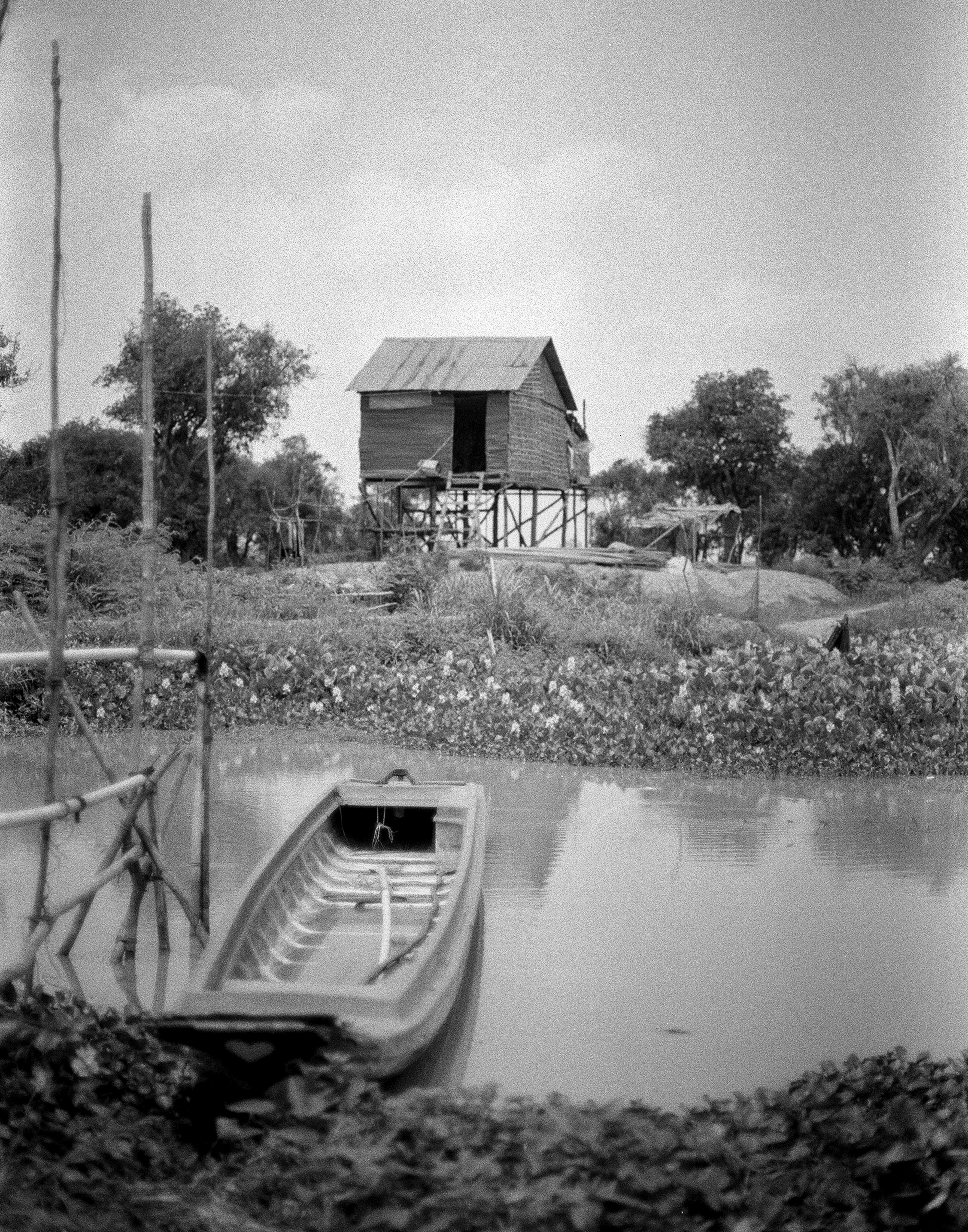 Rural landscape with traditional stilt house and moored boats on calm water