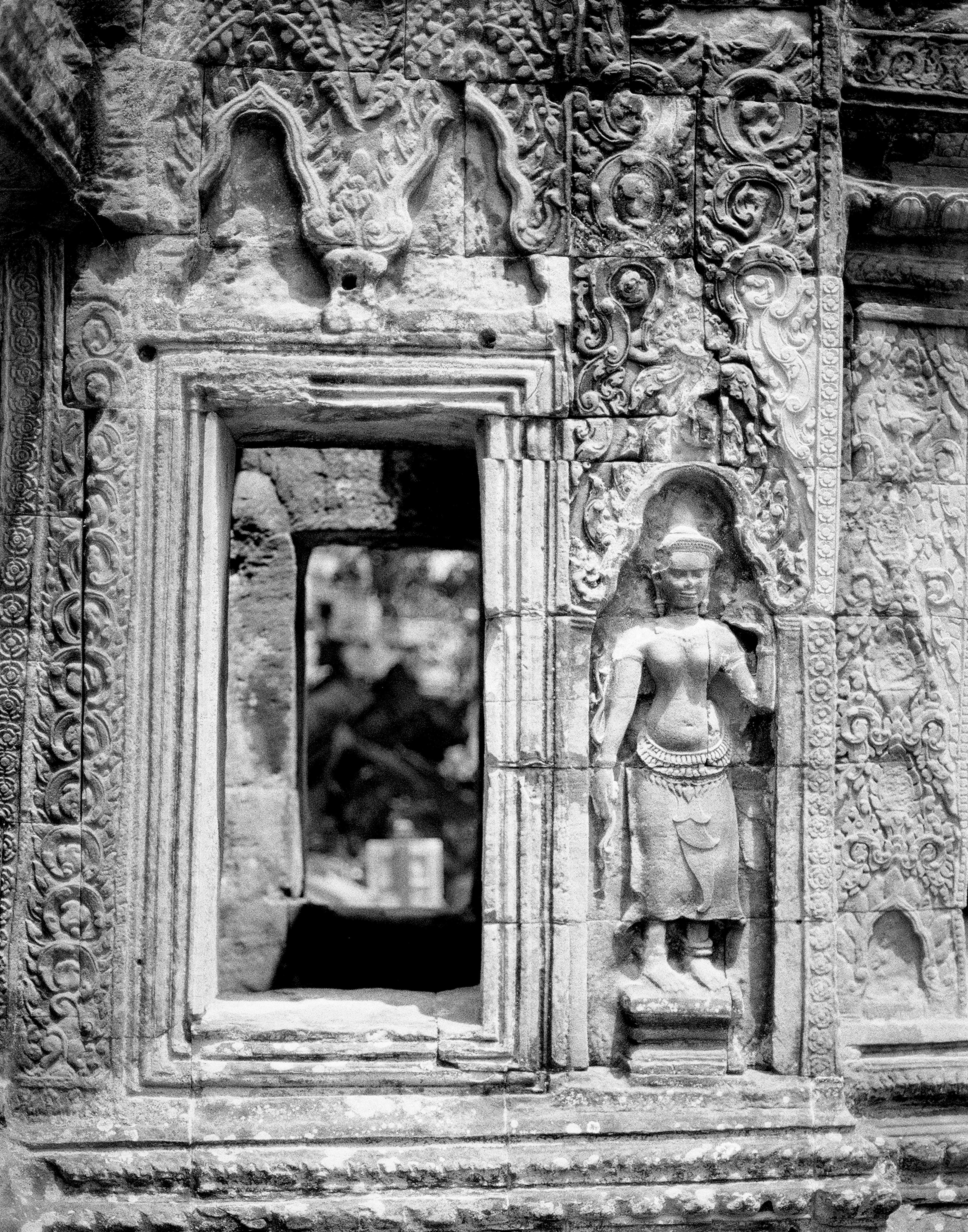 Ornate temple doorway with intricate carved reliefs and dancing apsara figure sculpture