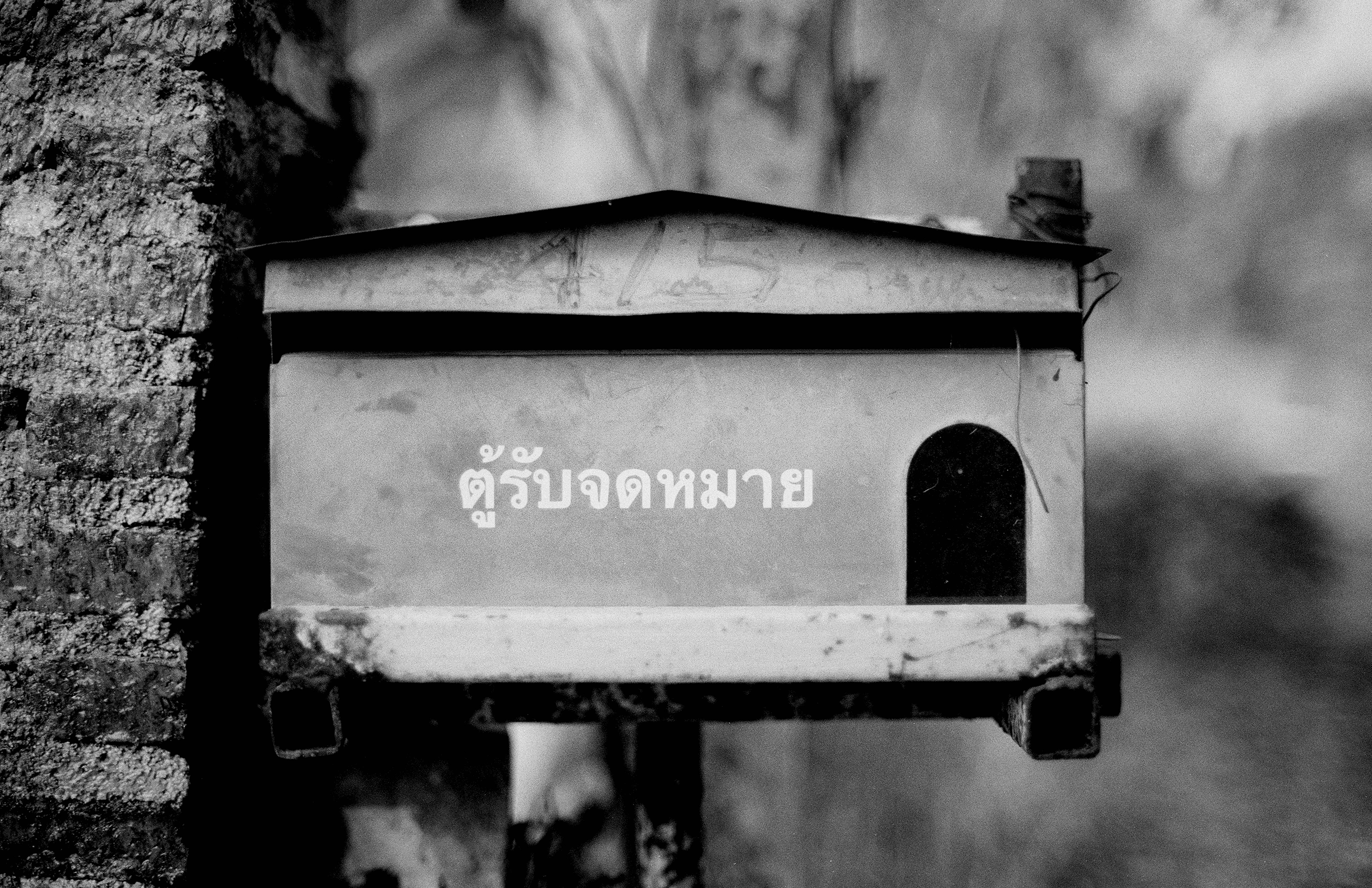 Traditional Khmer spirit house altar with Thai script inscription on whitewashed wall