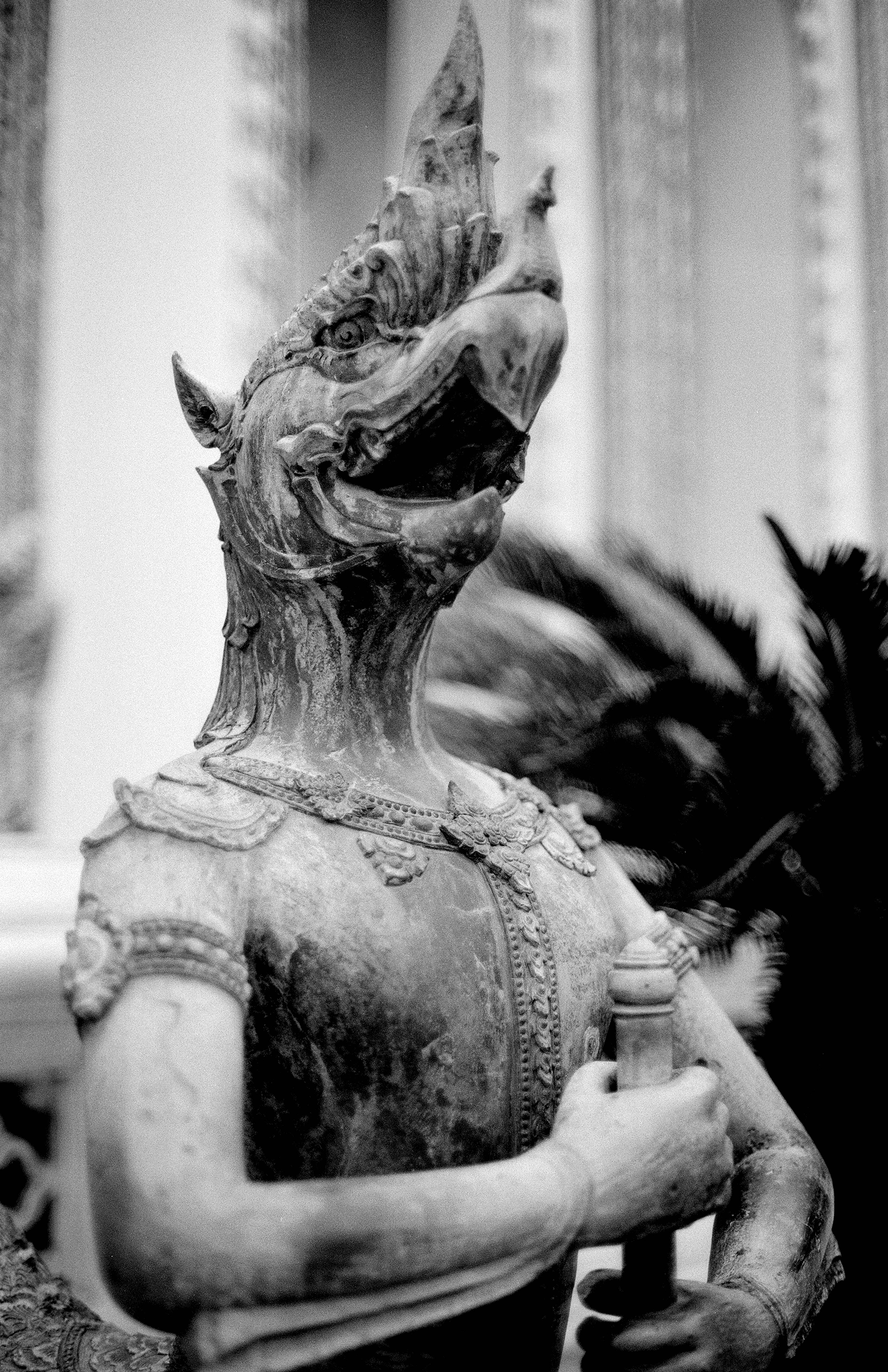 Mythical Garuda or Kinnara bronze statue detail with feathered wings at Thai temple