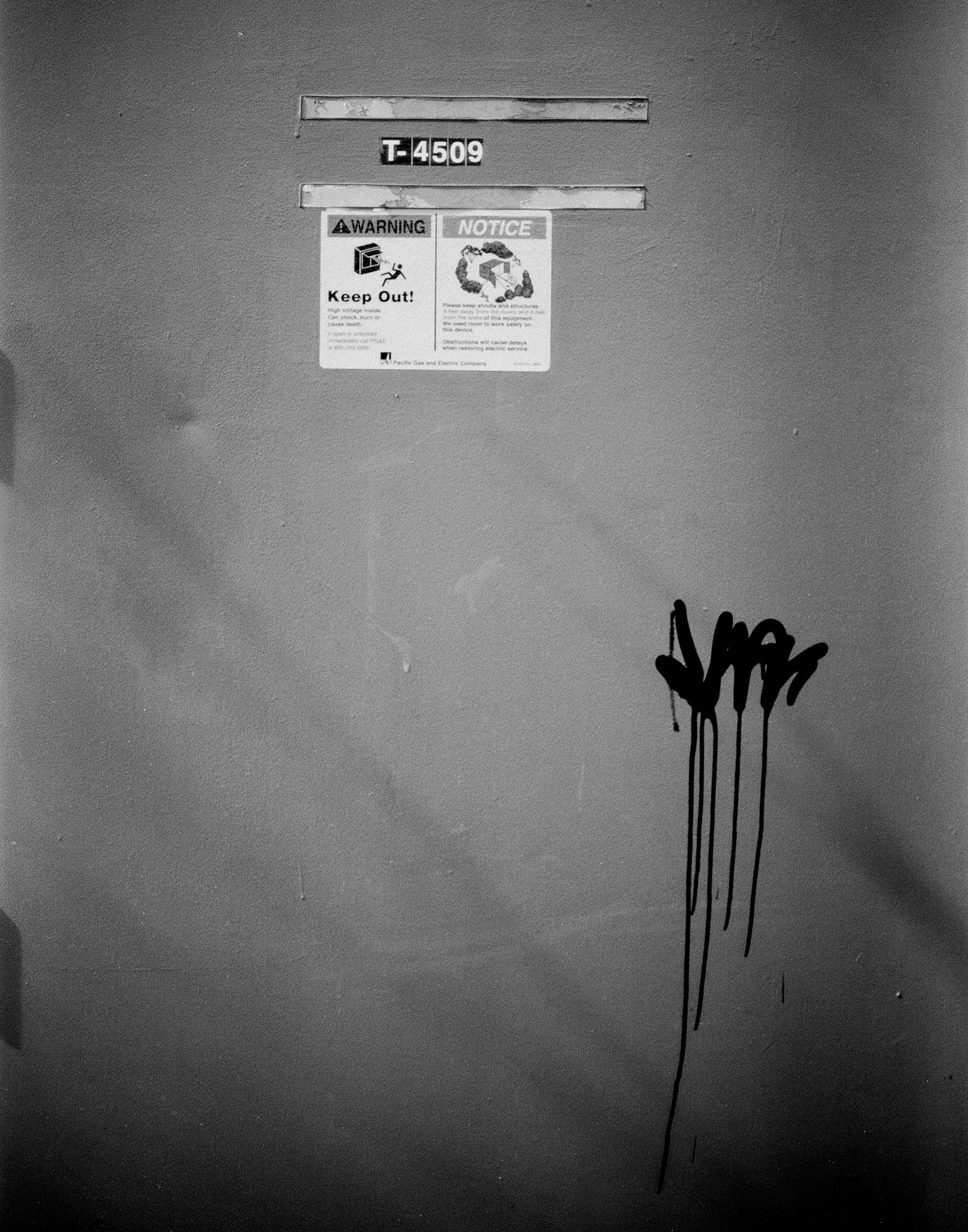 Industrial wall with F-4509 identifier warning and notice signs reading Keep Out with black graffiti art dripping downward in minimalist composition
