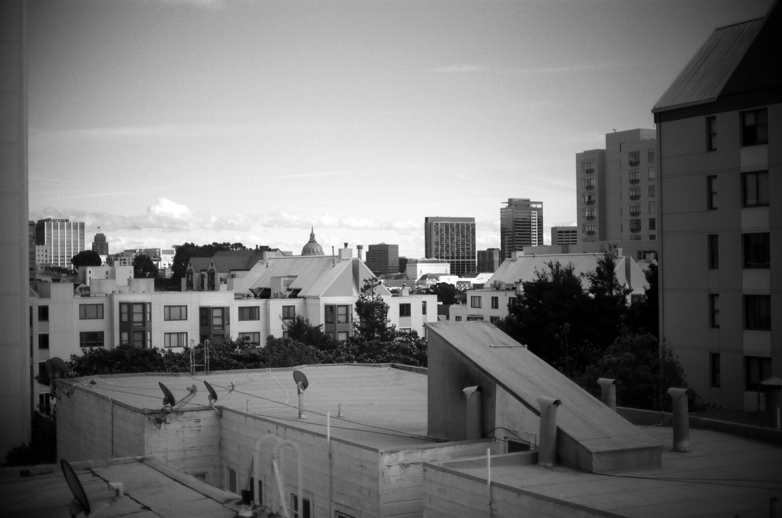 Rooftop cityscape view with white residential buildings and downtown skyline with church spire