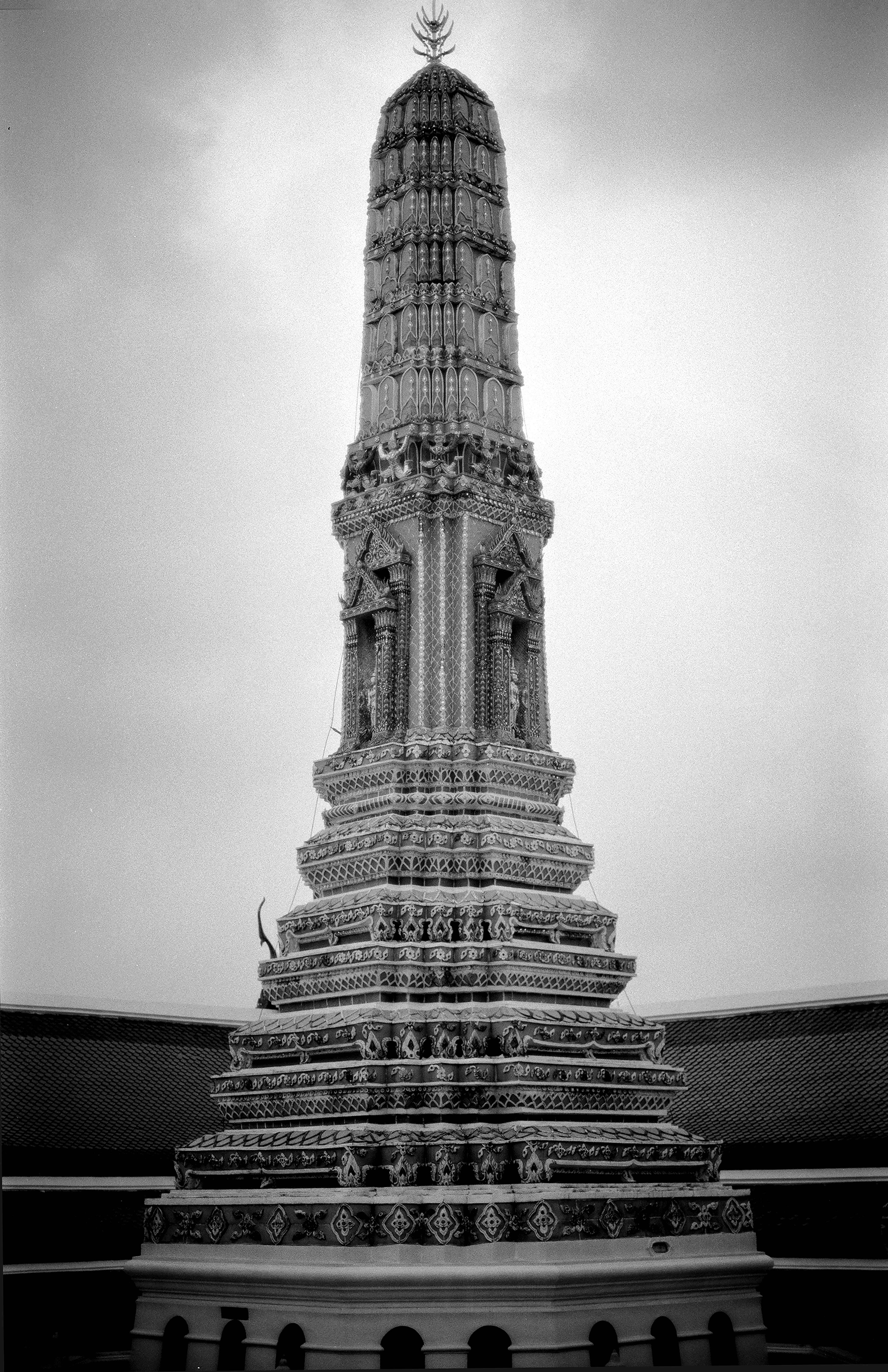Ornate Thai prang spire rising against sky with intricate Khmer-style carvings and decorative tiers at Bangkok temple