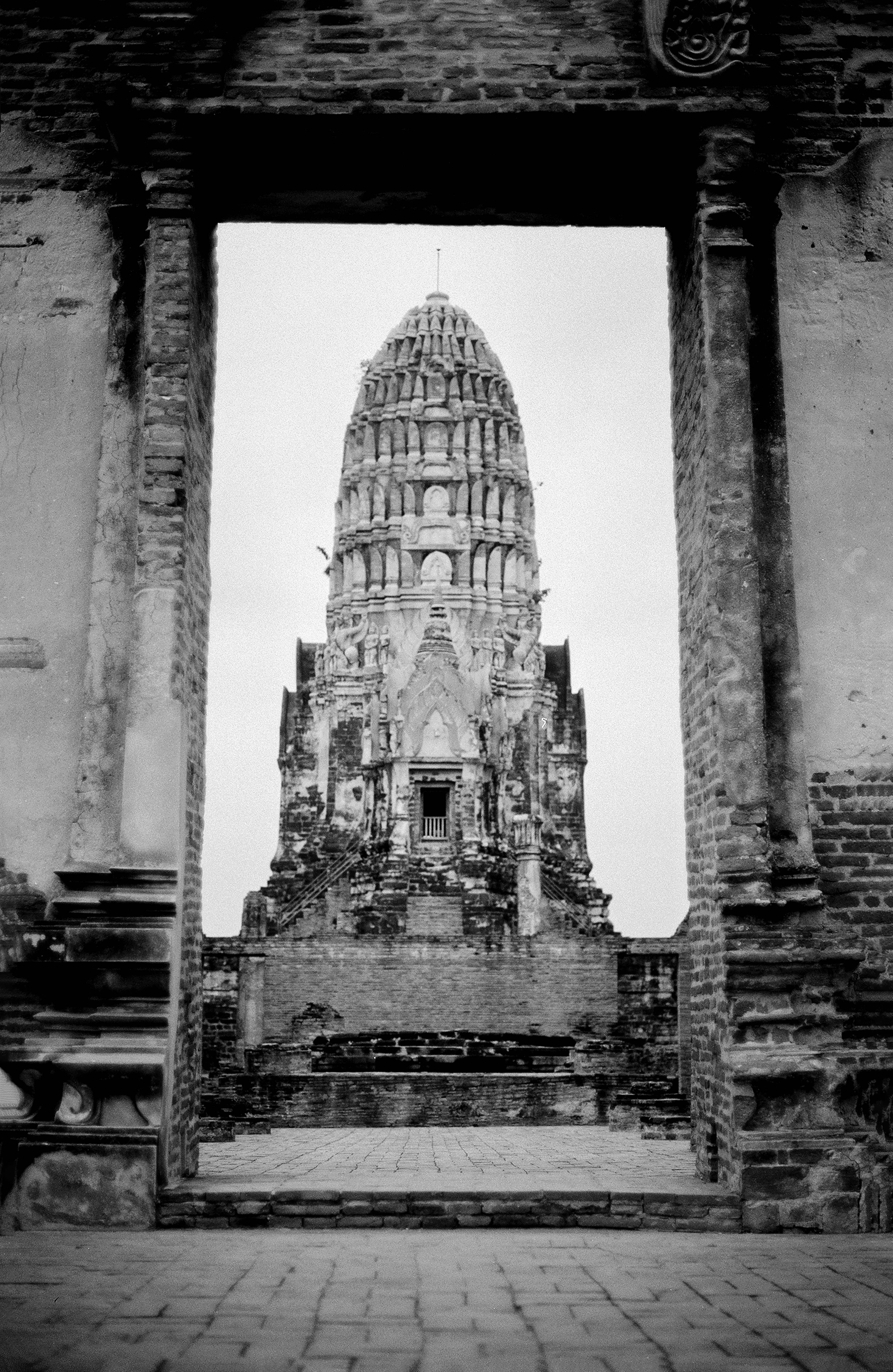 Ancient Khmer-style prang at Ayutthaya ruins dramatically framed through brick doorway archway