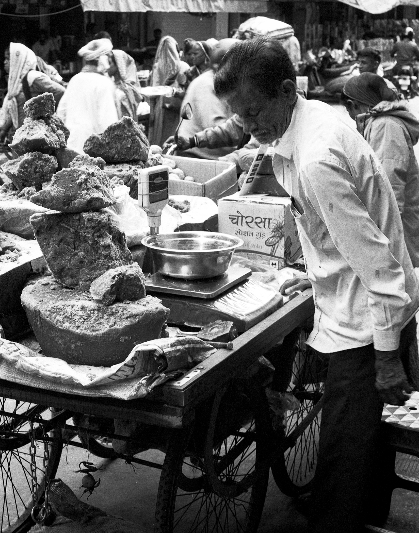 Black and white man preparing traditional Indian sweets with decorative balance scale and metal weighing cups