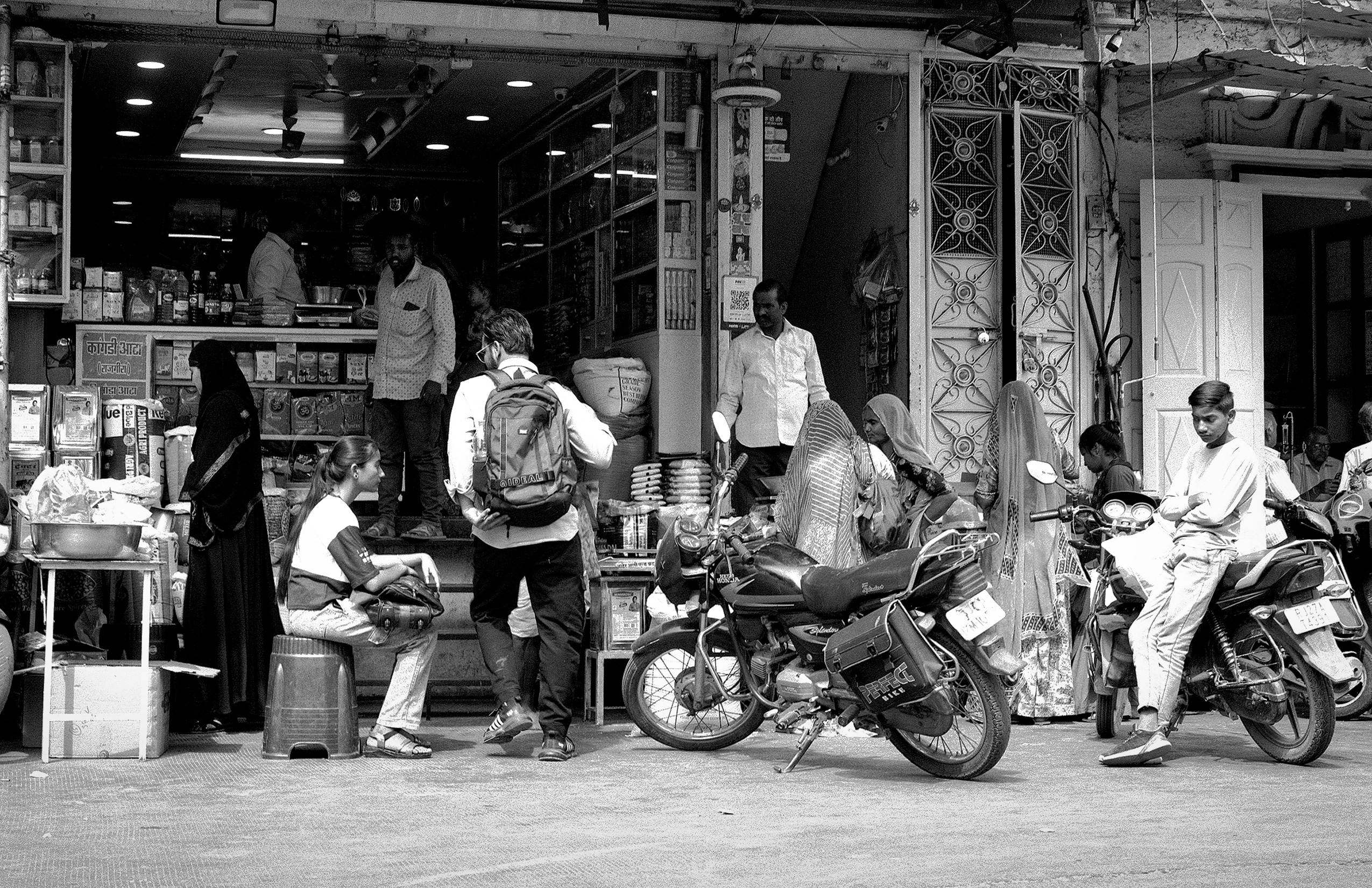 Black and white modern street scene with shop storefronts ornate gates motorcycles parked