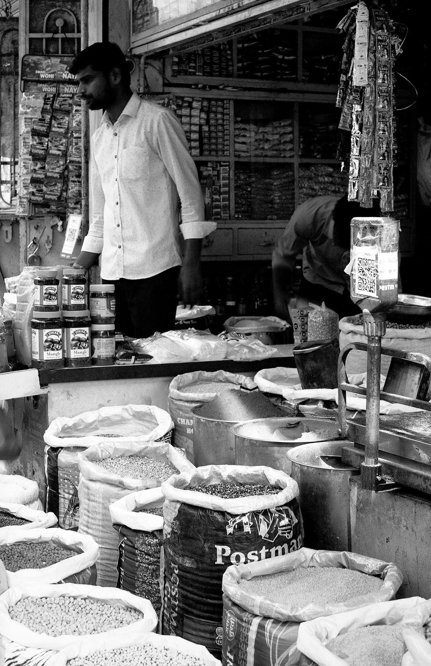 Black and white spice and grain merchant shop with white cloth bags of merchandise colorful containers