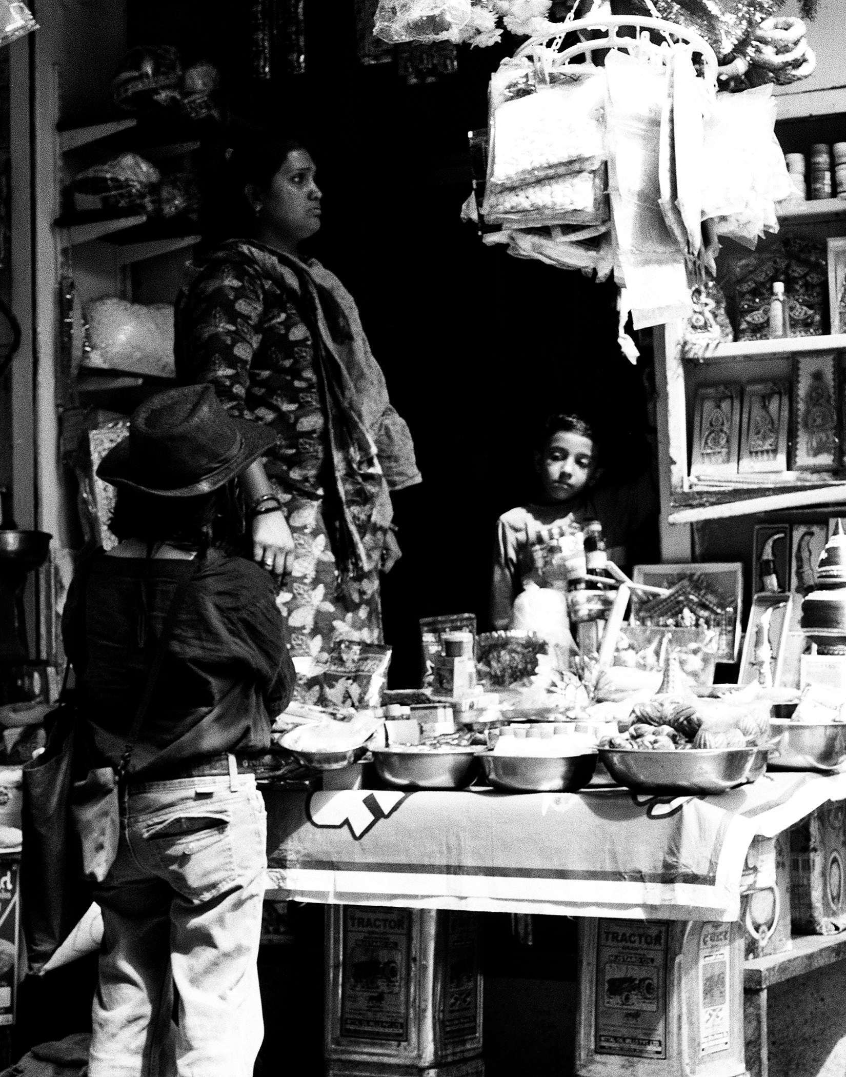 Black and white woman and child preparing food in modest home cooking vessel on stand