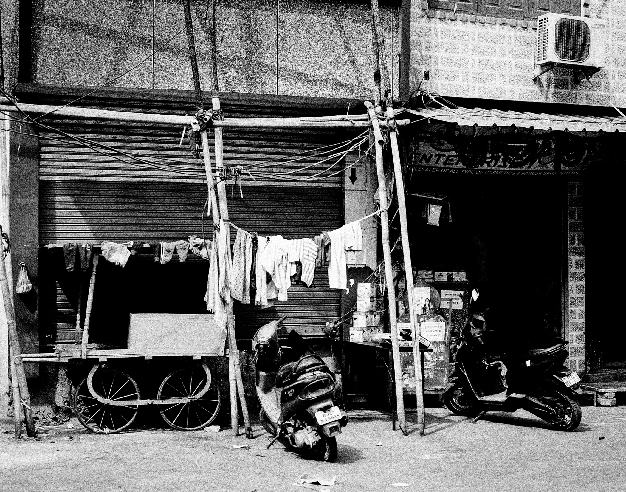 Black and white storefront with hanging laundry clothes on metal frame motorcycles parked outside