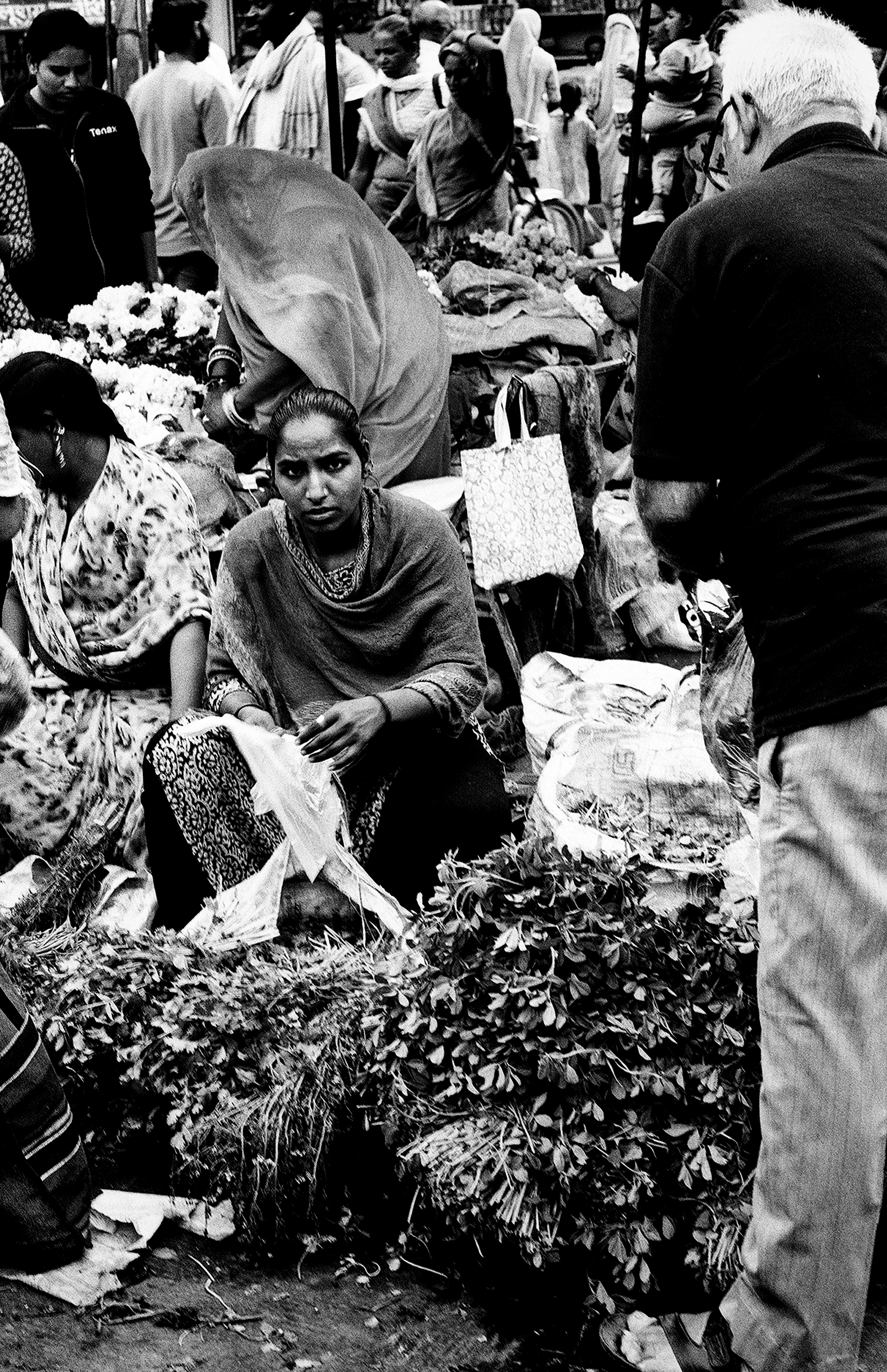 Black and white women and elderly man at flower vegetable market selling fresh blooms and garland