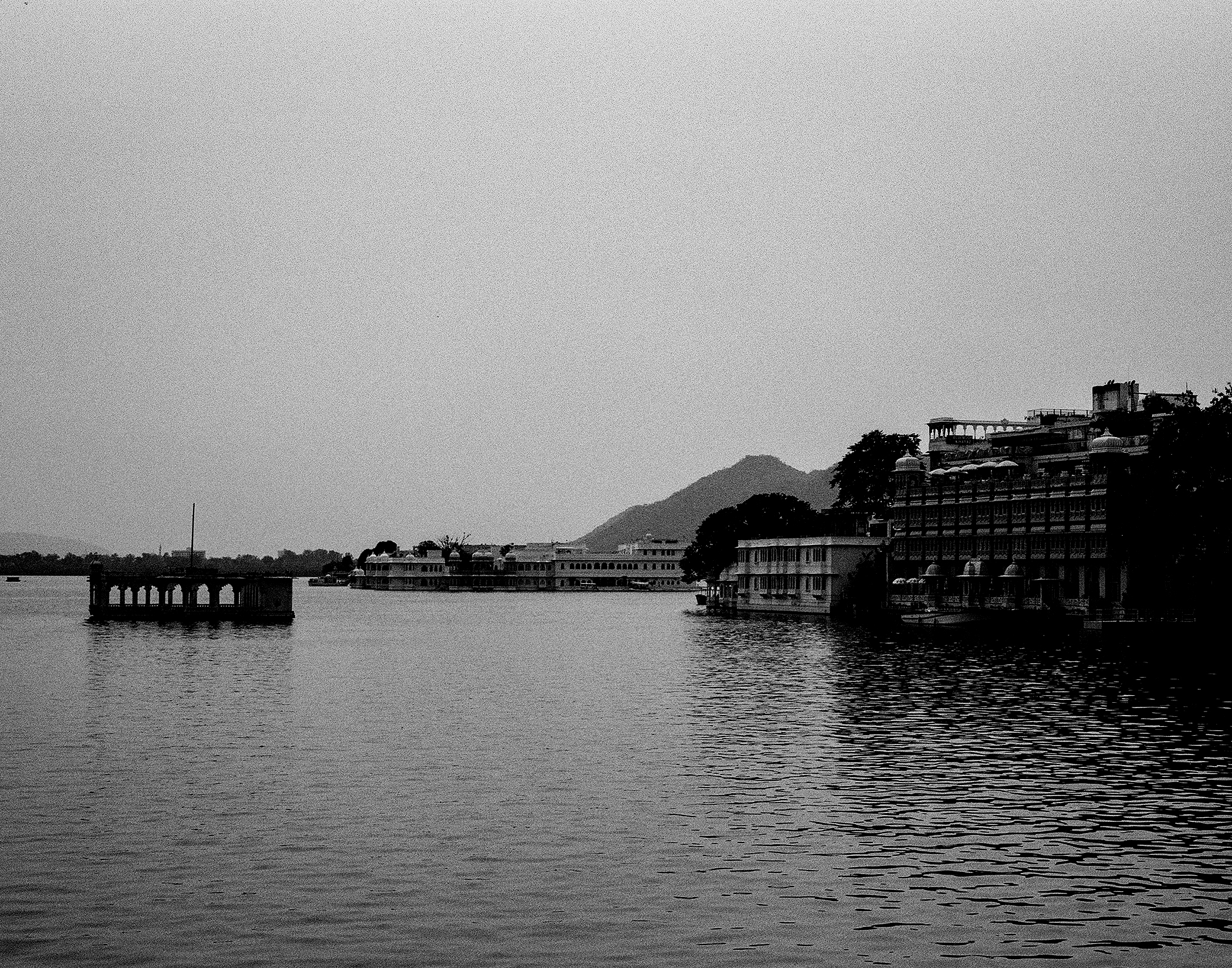 Black and white Udaipur lake panorama with palace complex mountains reflected in still water
