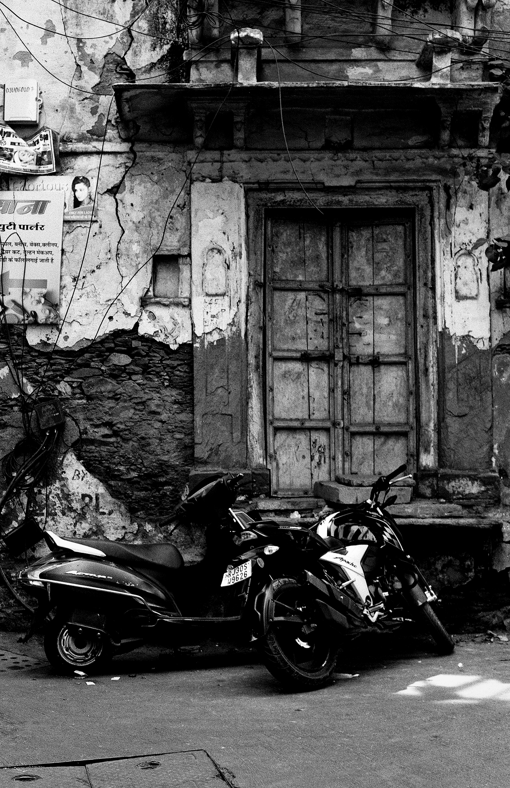 Black and white weathered building facade with parked motorcycles and hanging laundry