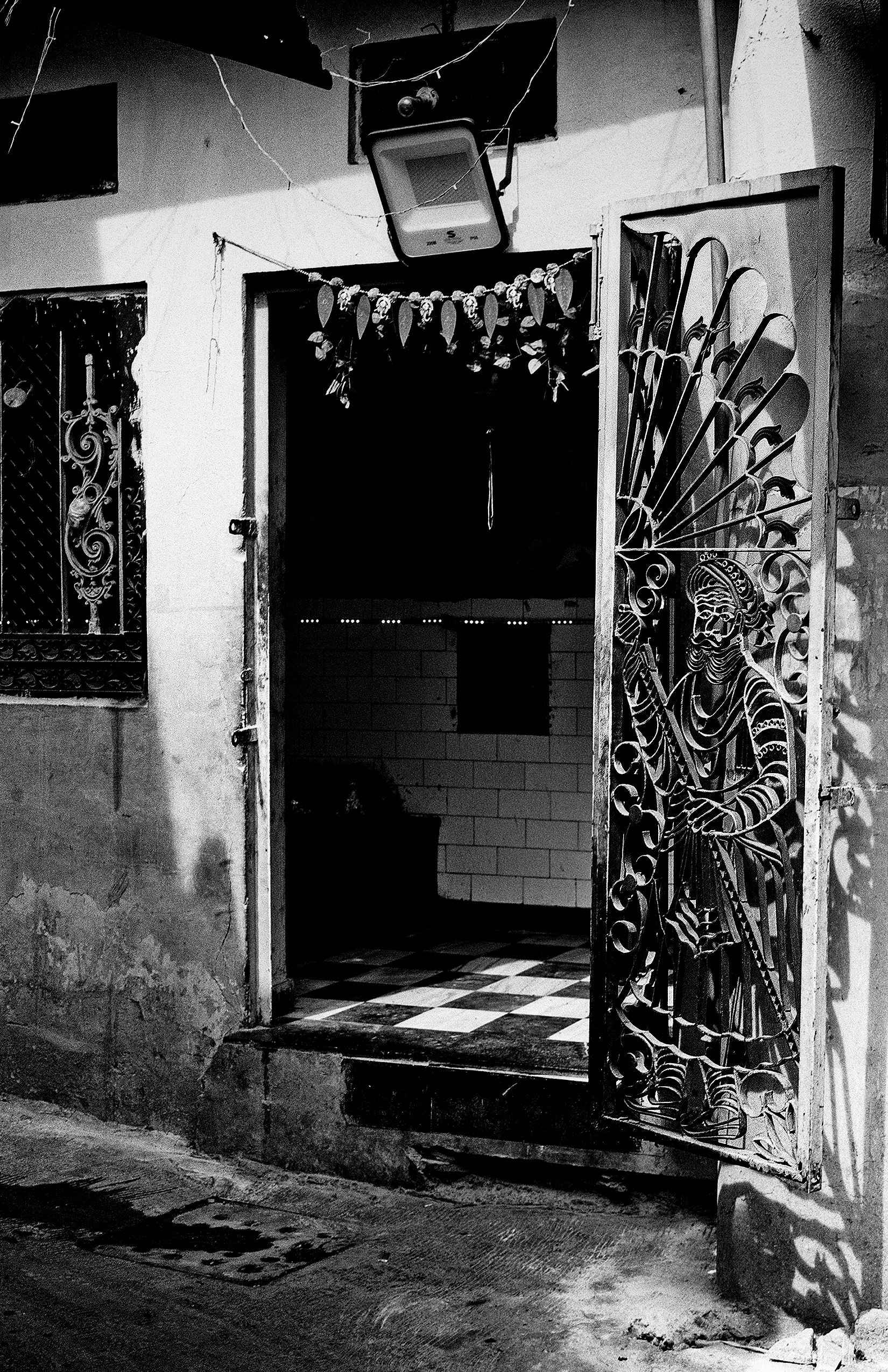 Black and white ornate metal gates with intricate peacock designs and hanging decorative elements