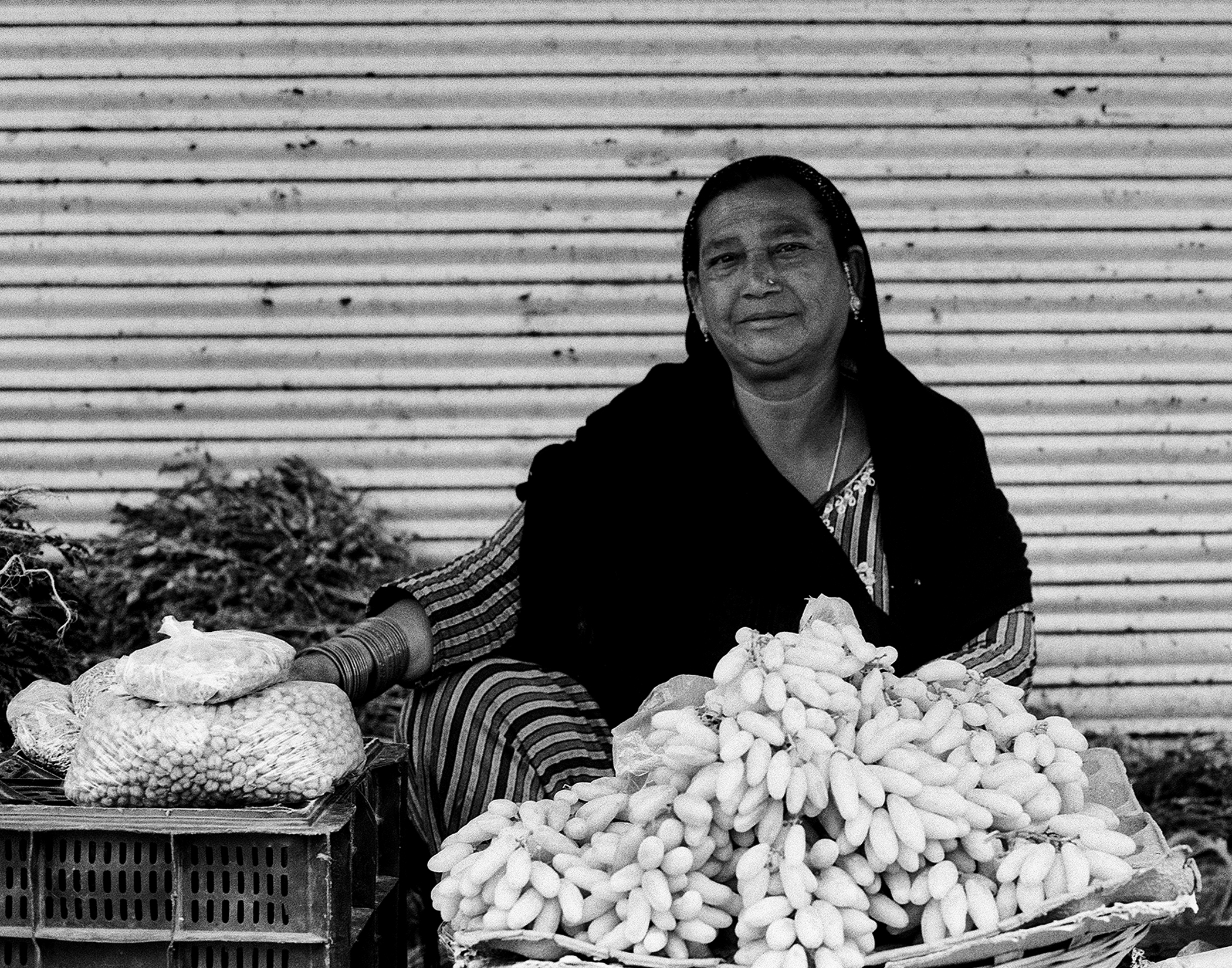Black and white woman at market stall with fresh produce vegetables and traditional clothing