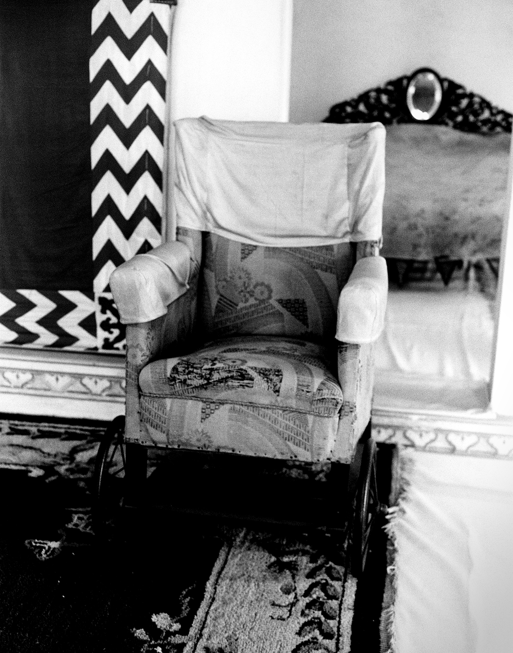 Black and white ornate upholstered chair with patterned textiles in decorated palace interior
