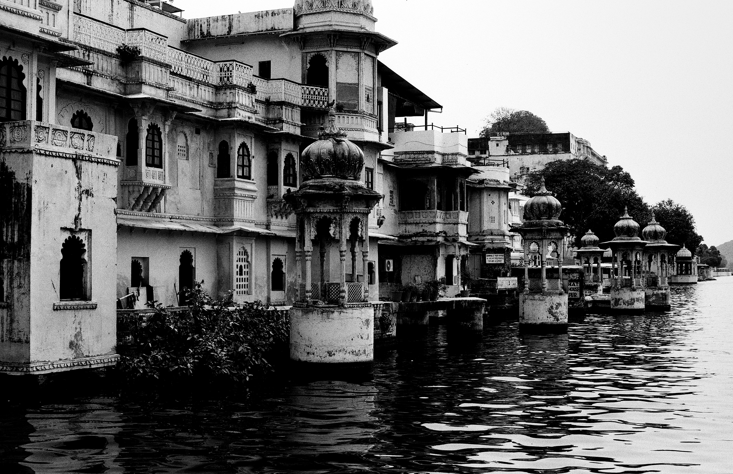 Black and white lakeside palace complex with domes minarets and ornate buildings reflected in water
