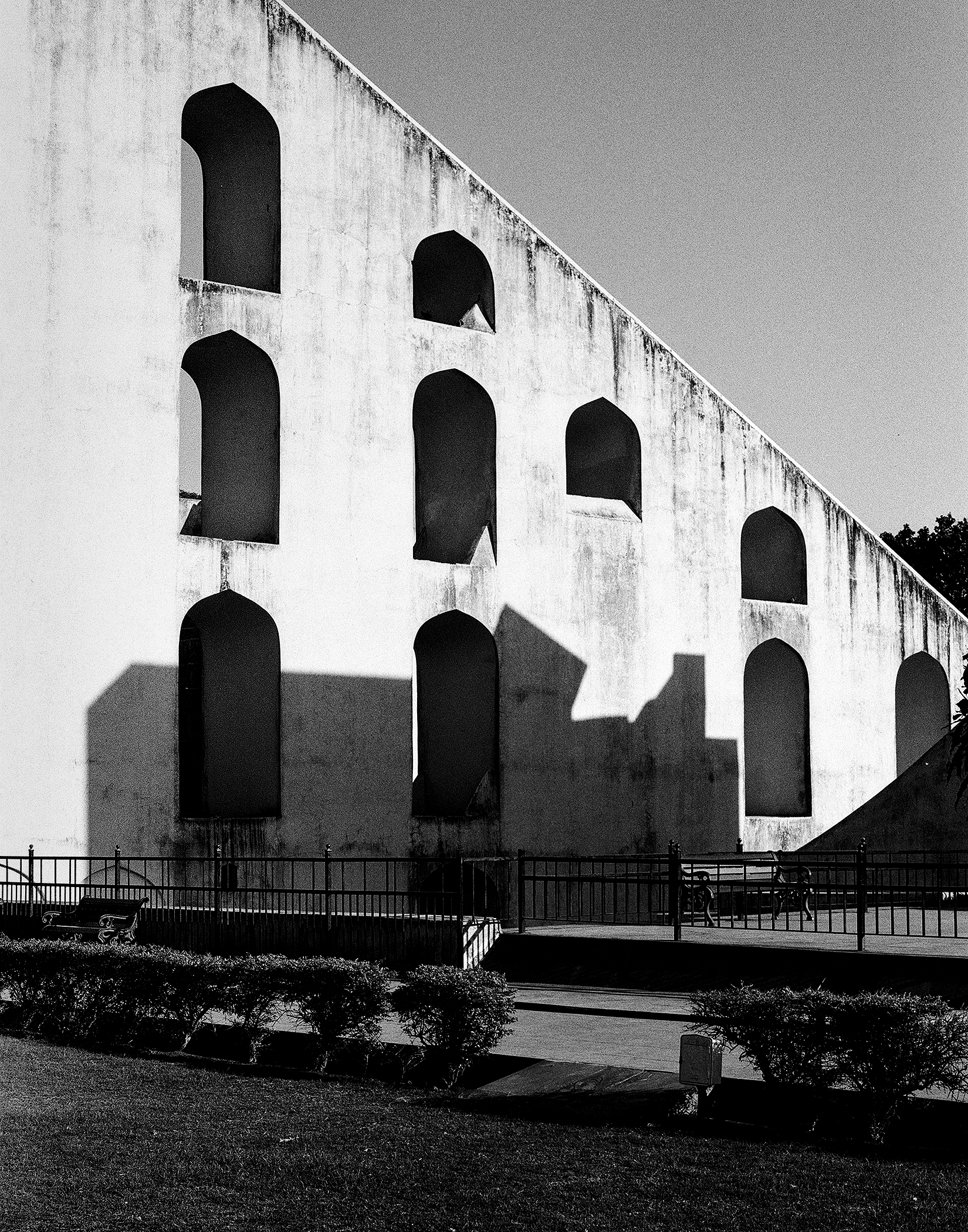 Black and white modernist white tower structure with multiple geometric arches and shadow patterns