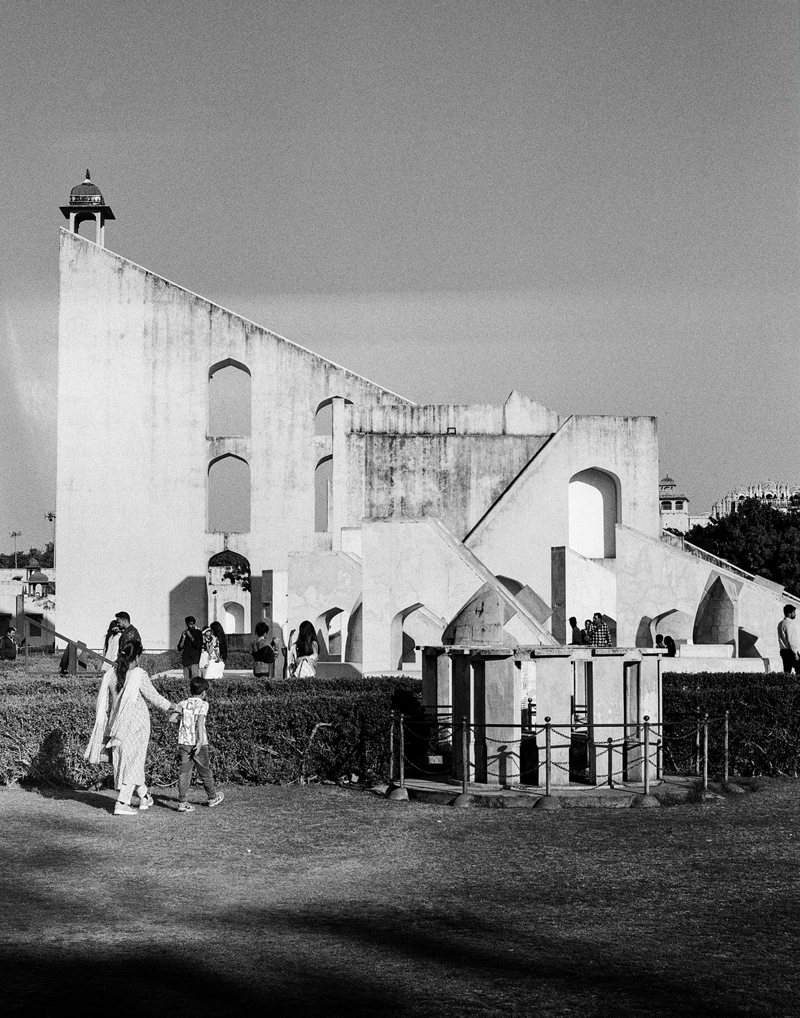 Black and white religious structure with minaret tower and visitors gathered in courtyard