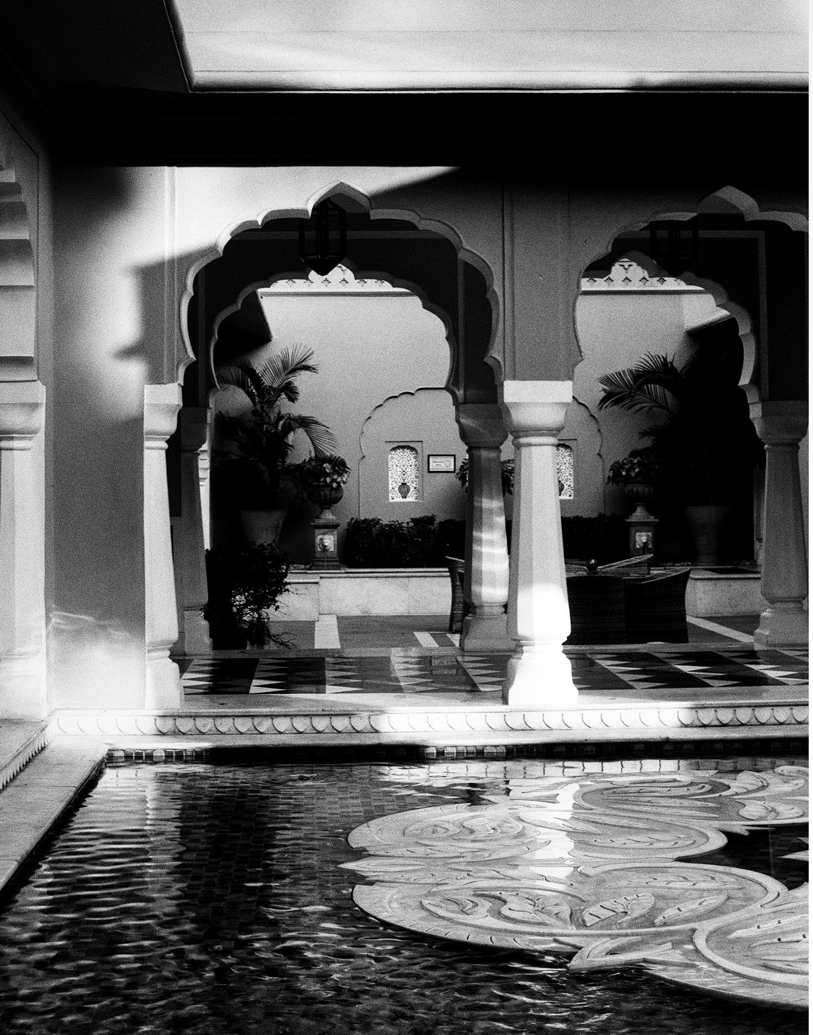 Black and white palace courtyard with ornate arches reflecting pool and intricate geometric tilework