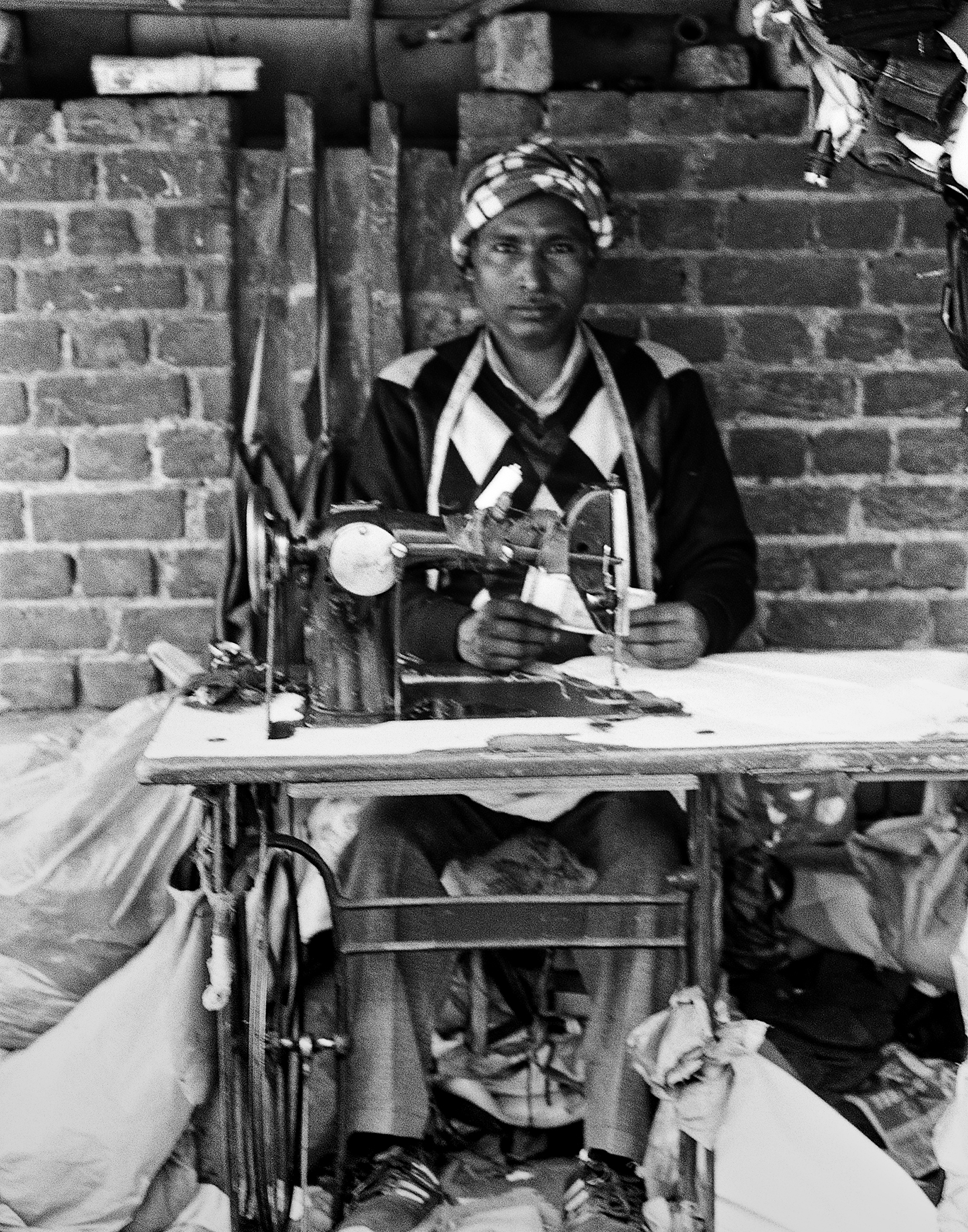 Black and white craftsman working with traditional textile or craft materials on wooden workbench