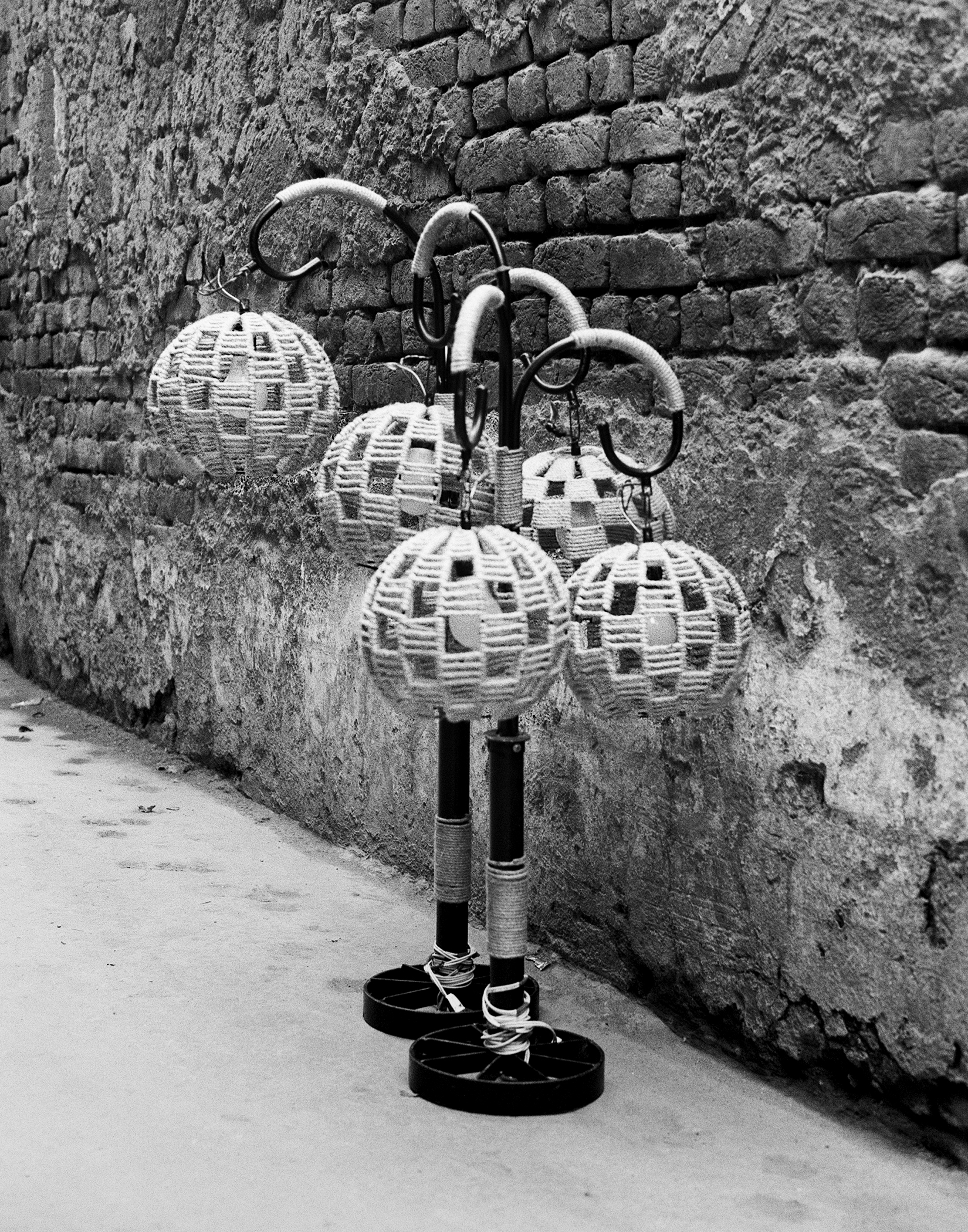 Black and white woven spherical ornaments with metal hooks hanging against ancient stone wall