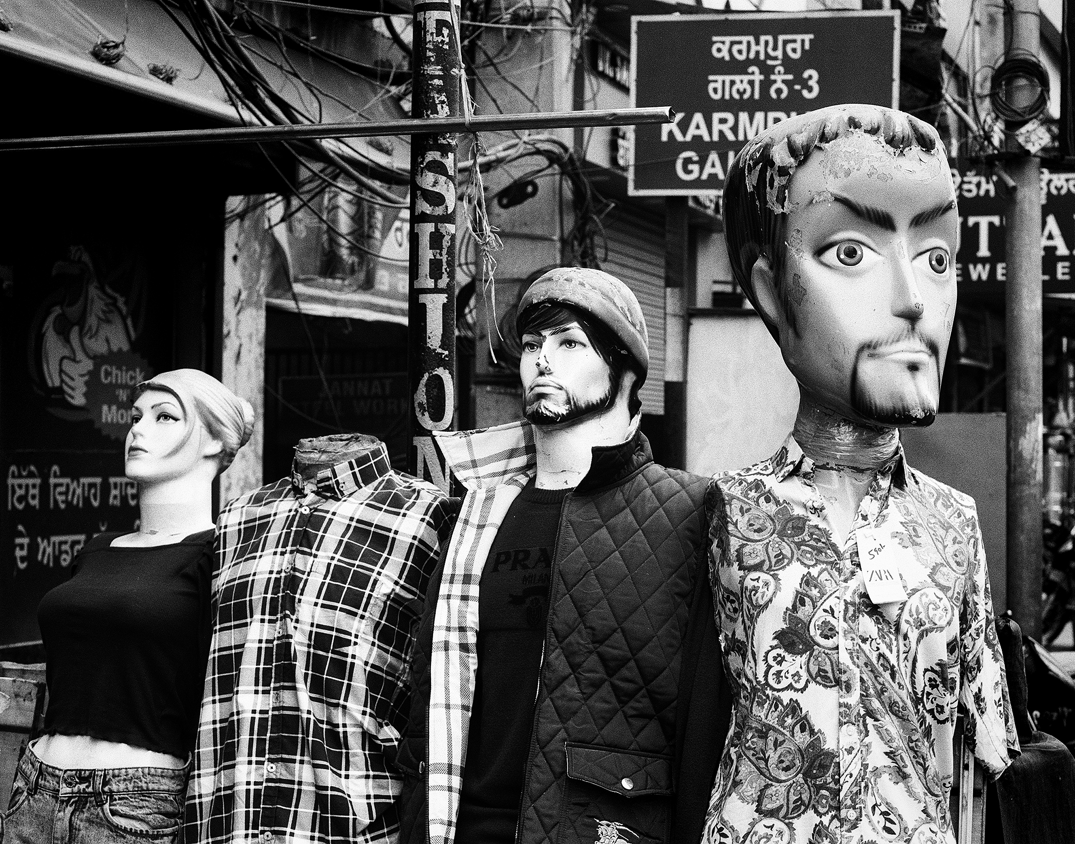 Black and white fashion store window mannequins displaying plaid shirts floral patterns
