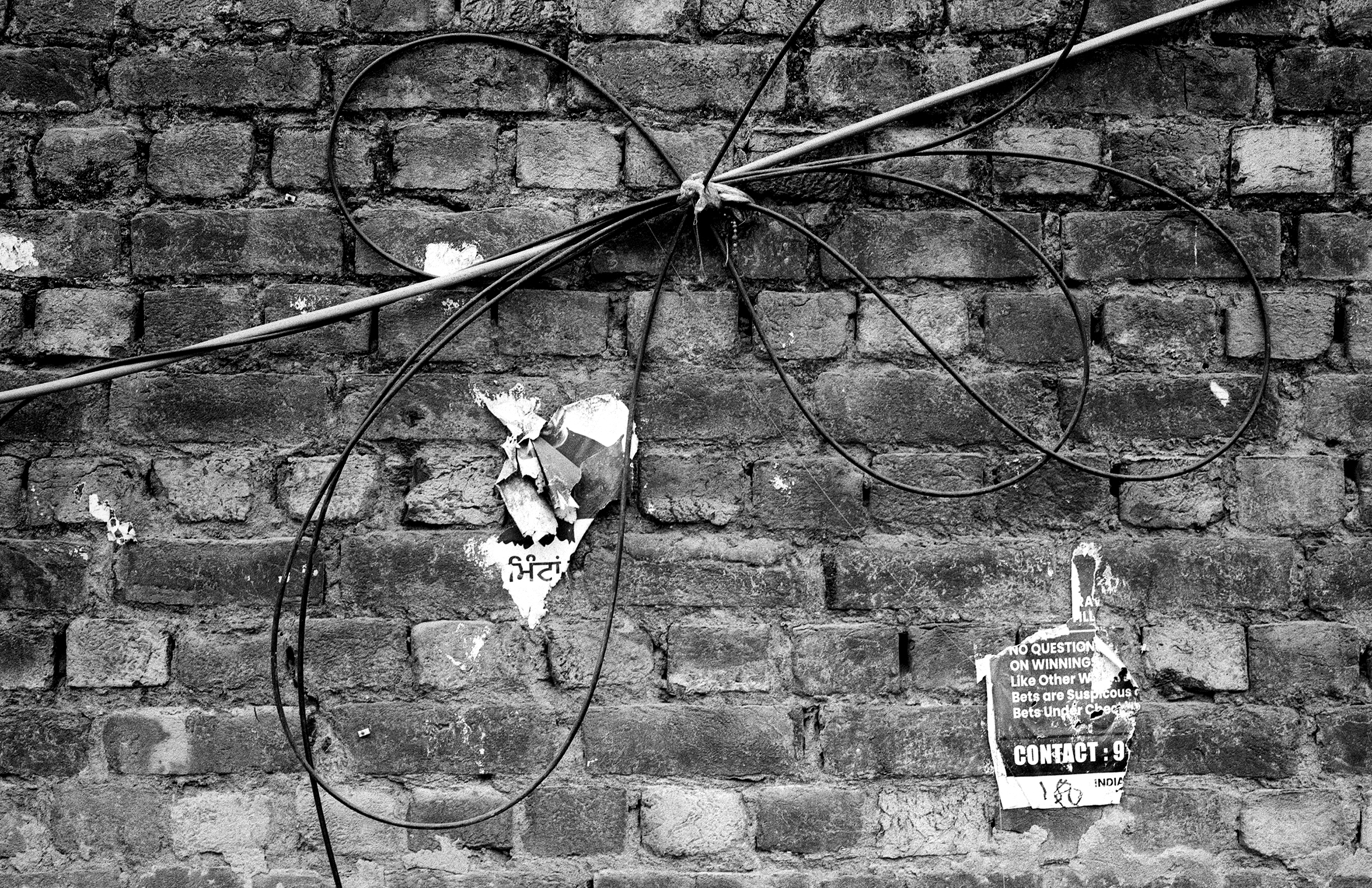 Black and white abandoned bicycle with tangled electrical wires against weathered stone wall