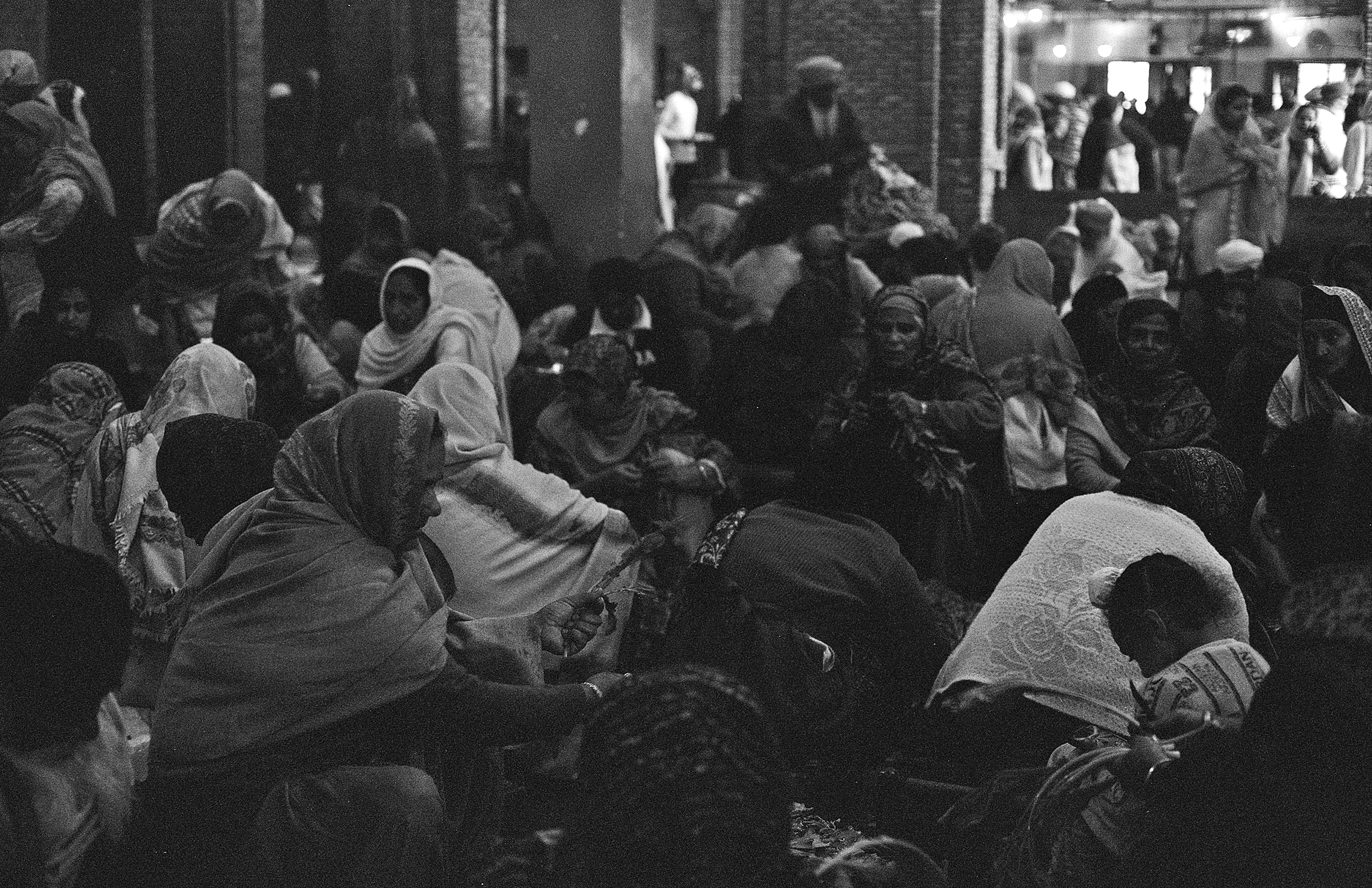 Black and white crowd of women in traditional dress at indoor religious gathering and celebration