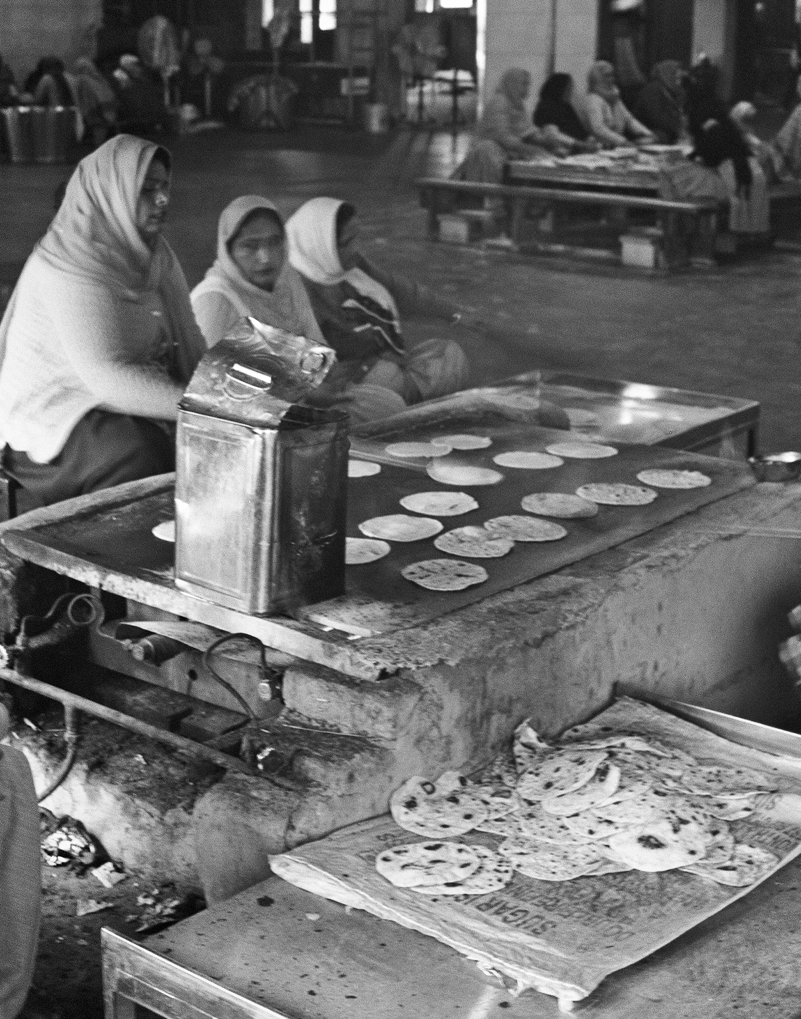 Black and white woman and child preparing traditional Indian flatbread on large cooking griddle