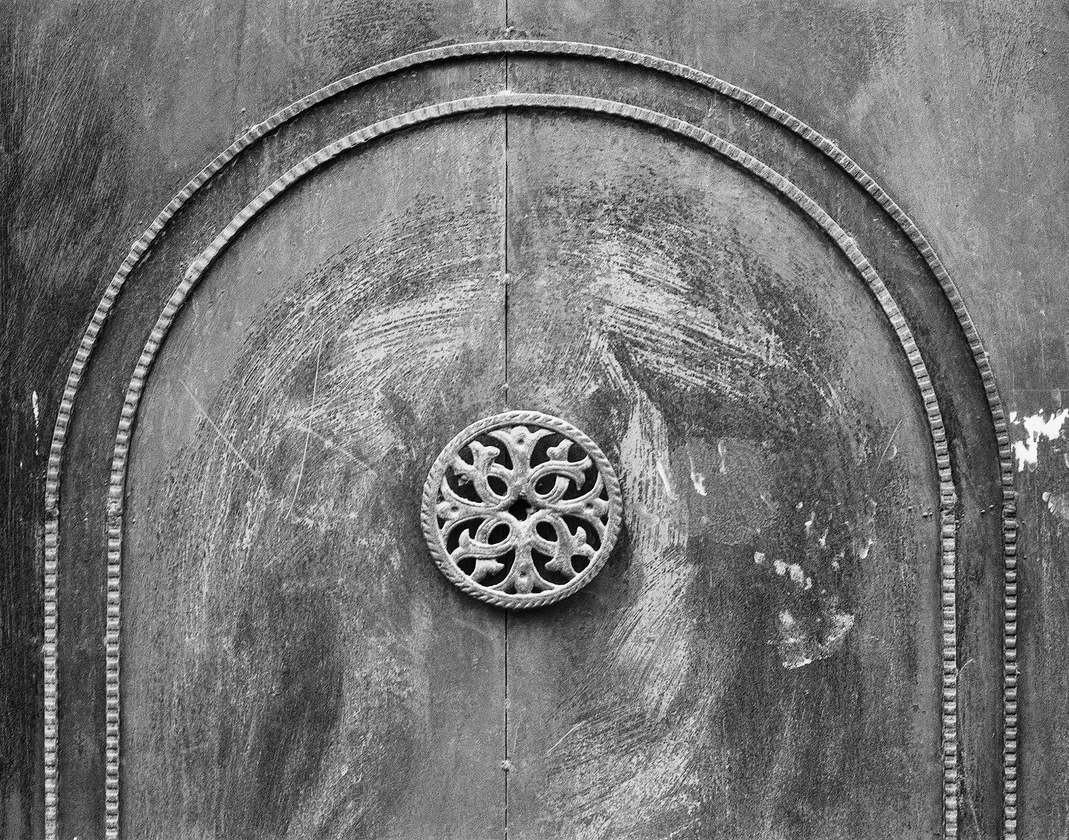 Black and white ornate carved wooden door detail with circular flower motif and decorative border
