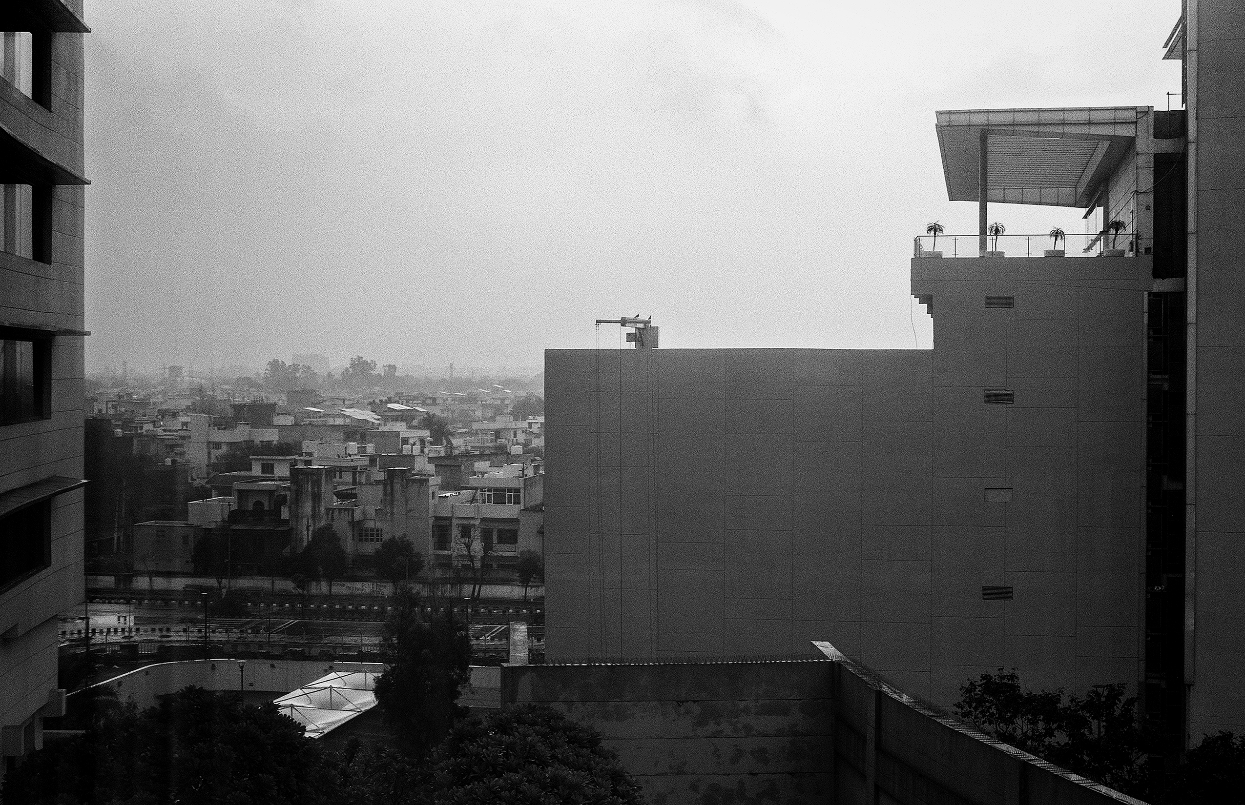 Black and white modern urban skyline panorama viewed from elevated vantage between buildings