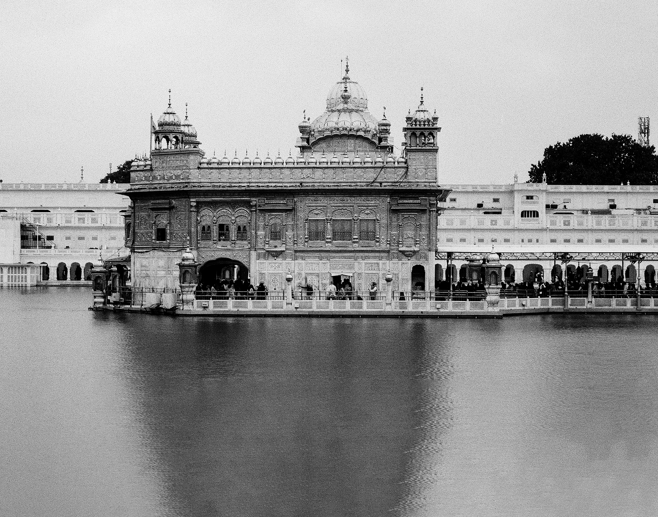 Black and white Harmandir Sahib Golden Temple across sacred pool with detailed latticed screens