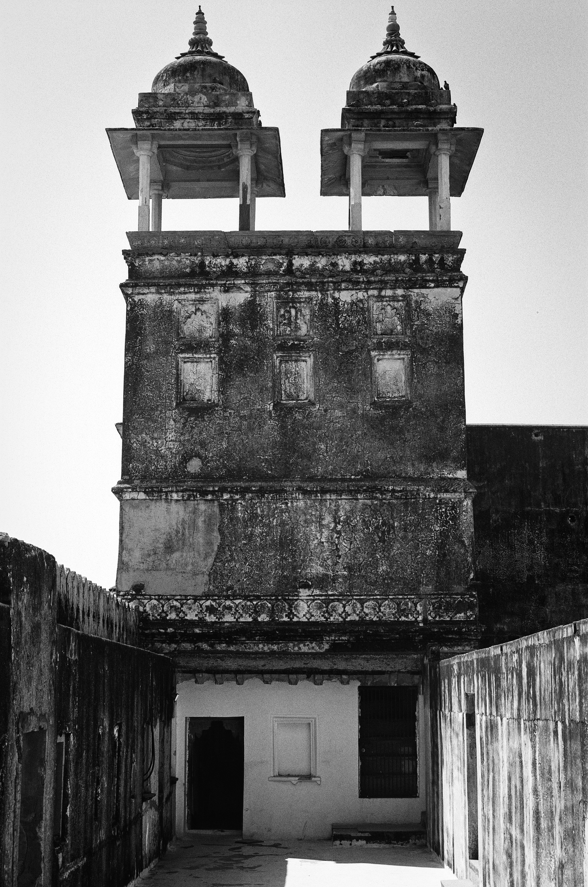 Black and white historic fort tower with weathered arched windows domed cupolas and deteriorating facade