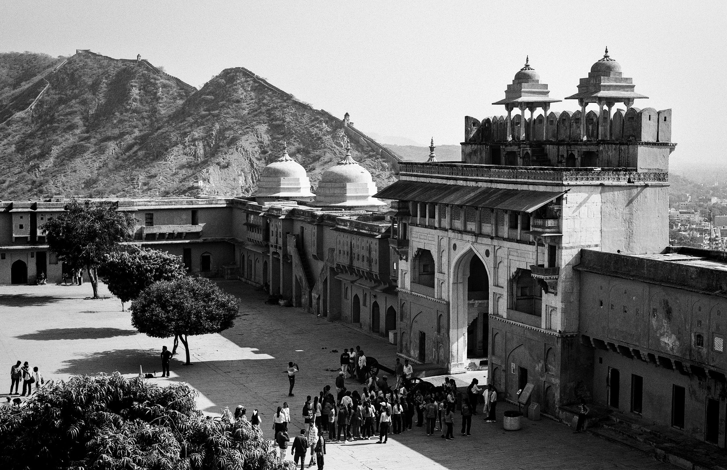 Black and white grand palace courtyard with crowds visitors white domes ornate railings and mountains