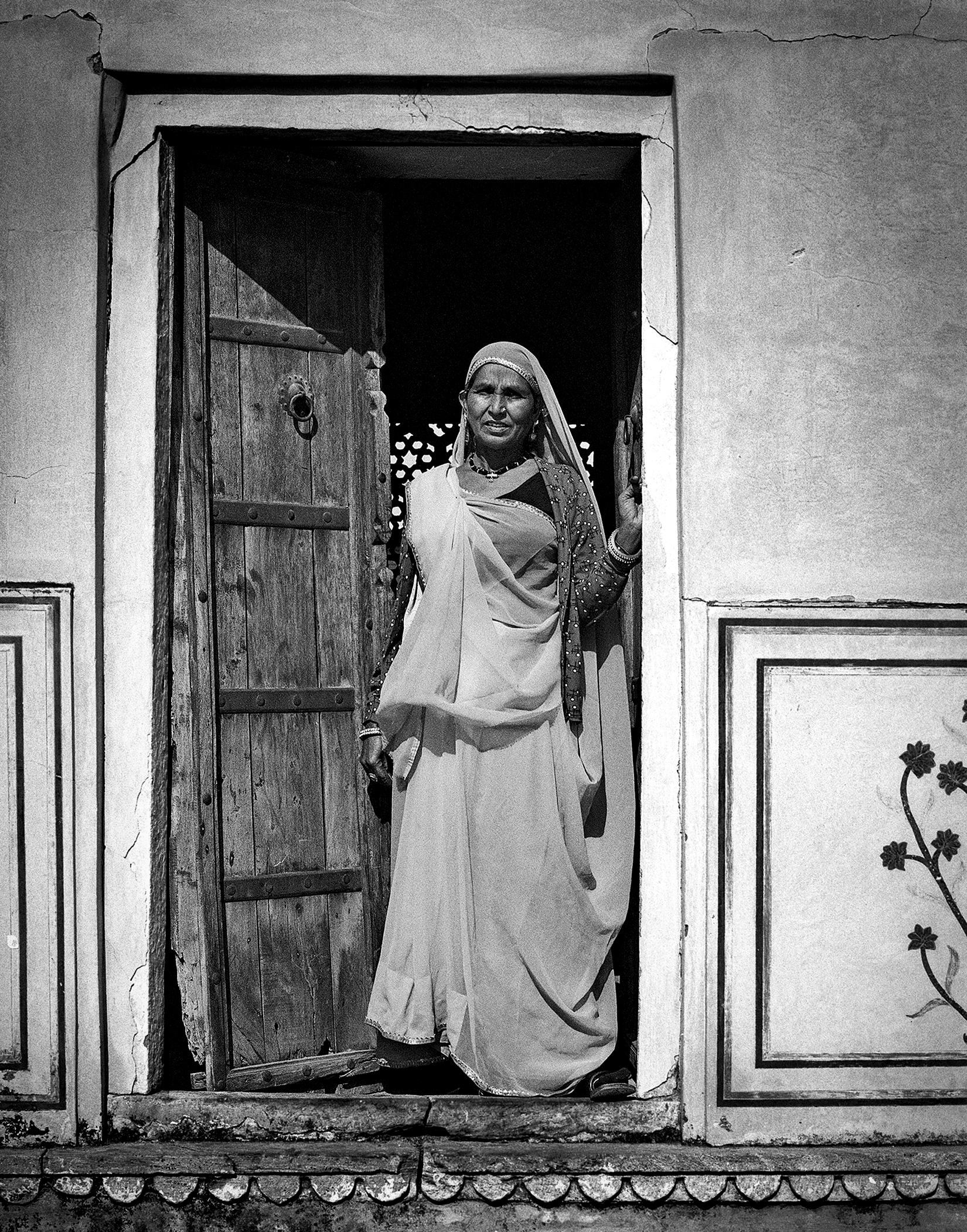 Black and white woman standing in wooden doorway wearing traditional white garments and head covering