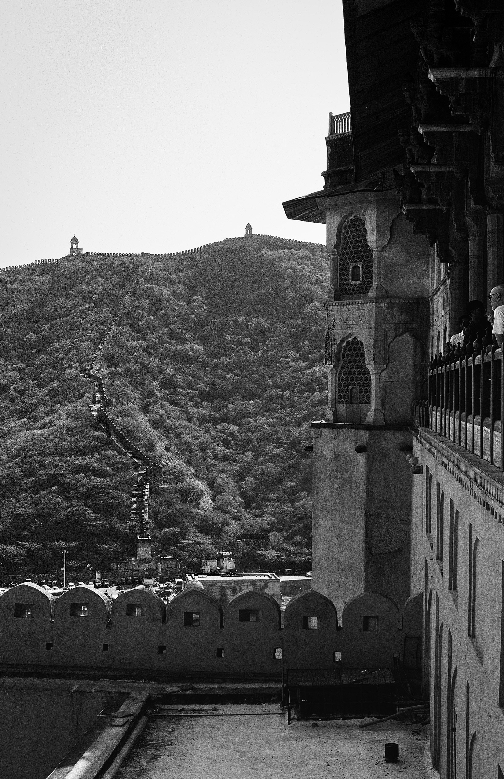 Black and white fort structure with ornate minaret overlooking green hillside with fortified walls
