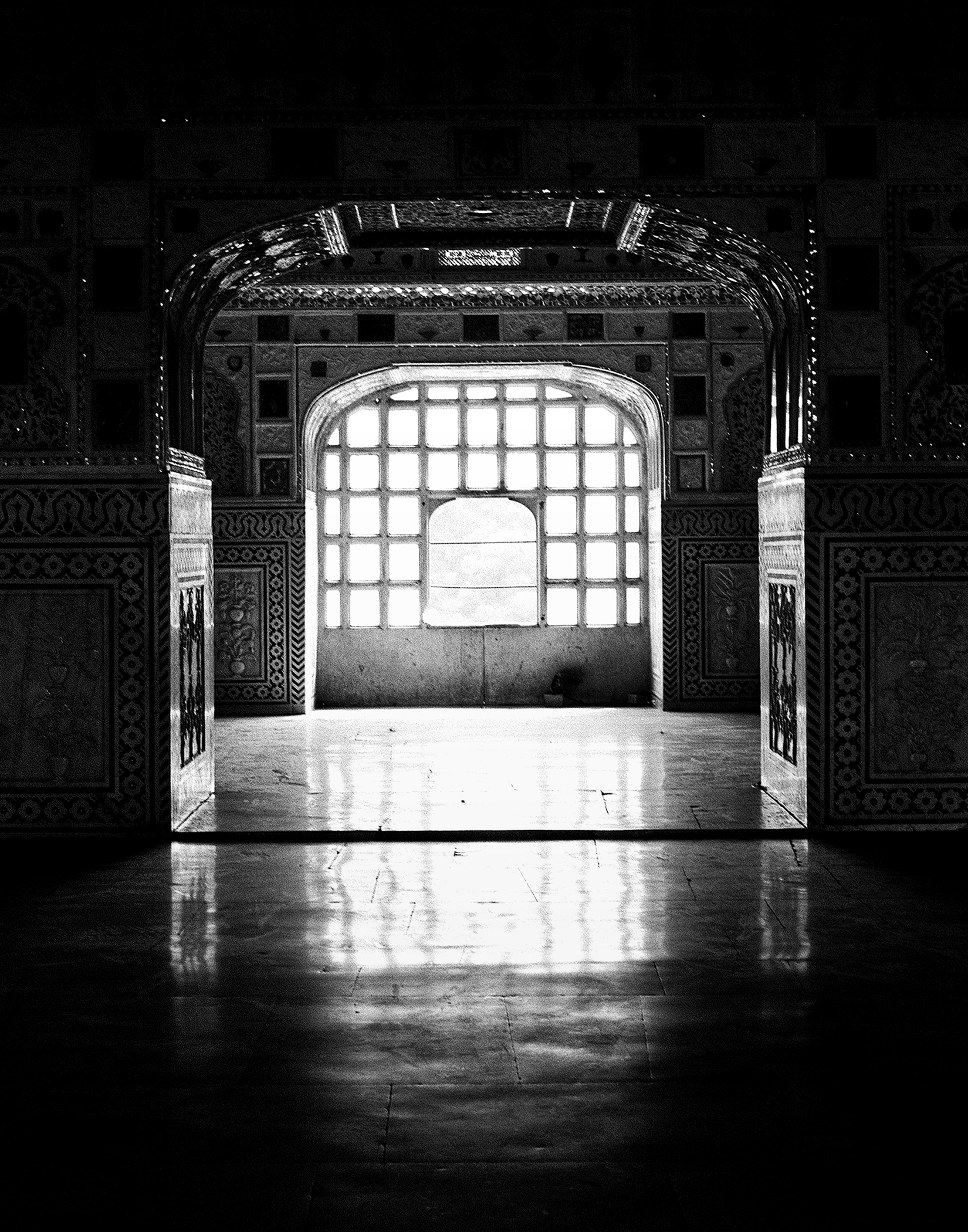 Black and white interior passage with arched doorway latticed window bright light geometric patterns
