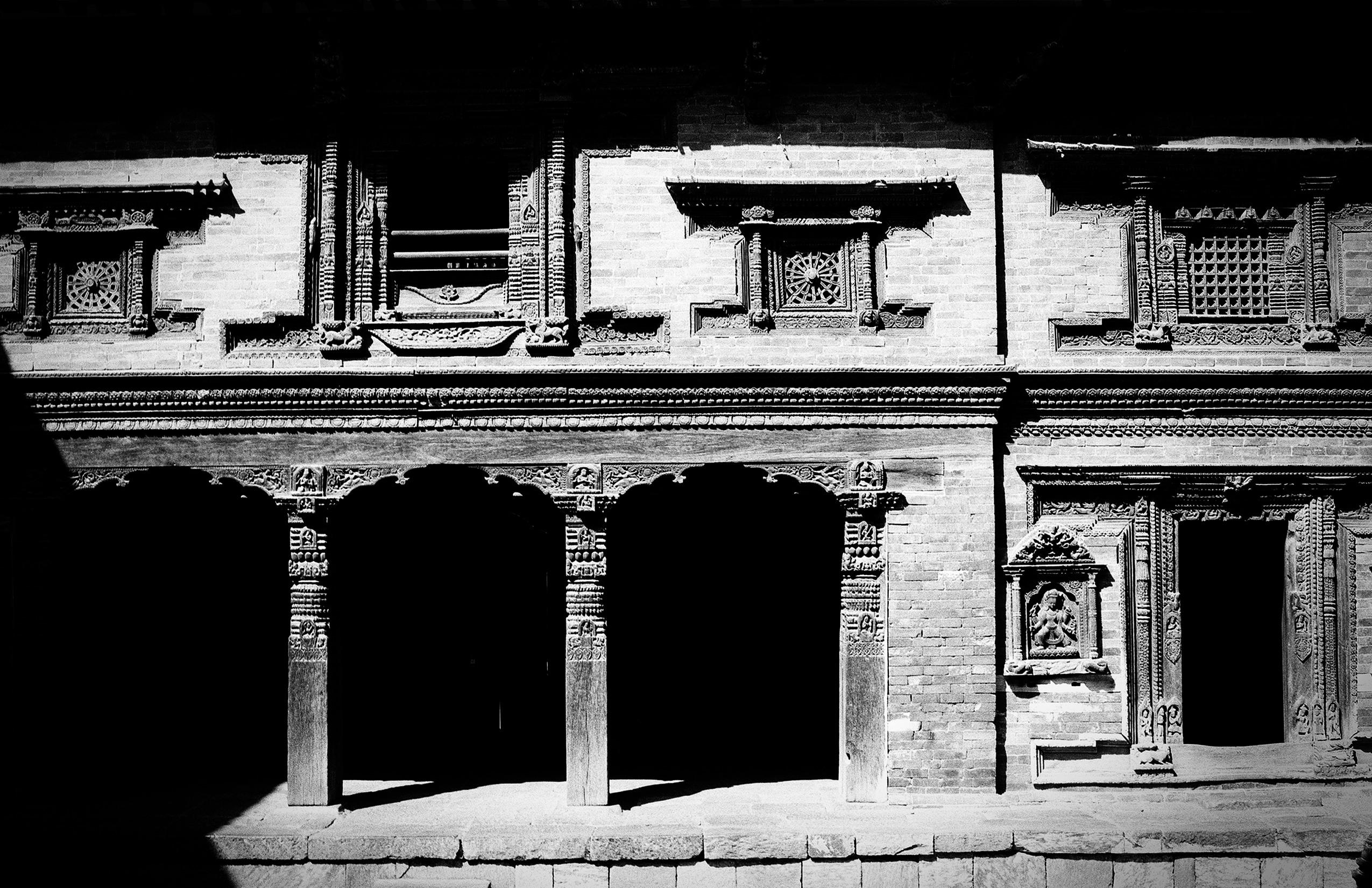 Traditional Newari architecture with ornate wooden windows and carved stone pillars