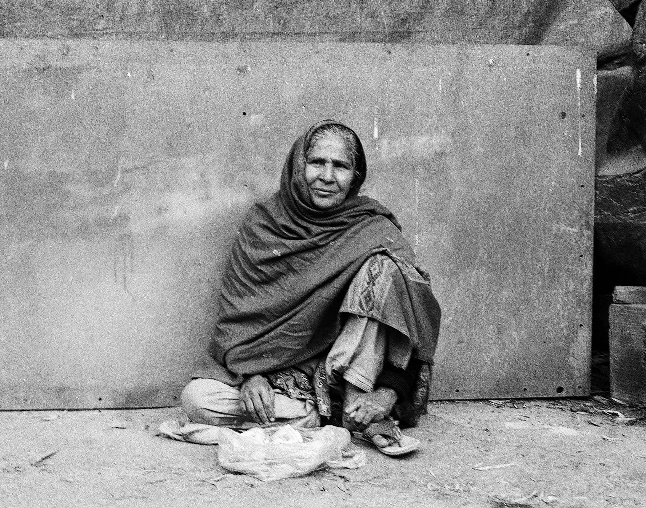 Woman in traditional dress sitting against weathered wall