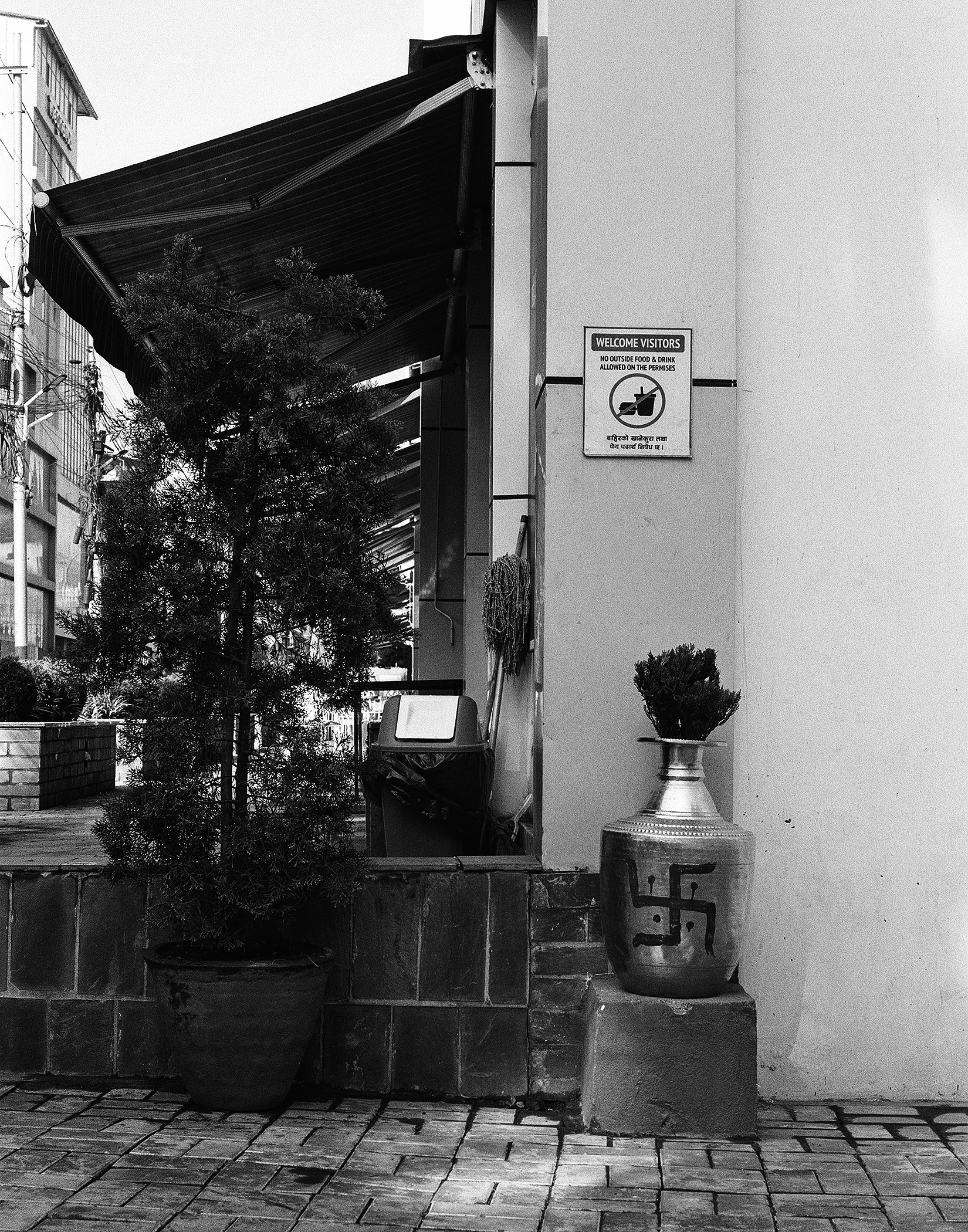 Modern temple entrance with welcome visitors sign and brass pot of flowers
