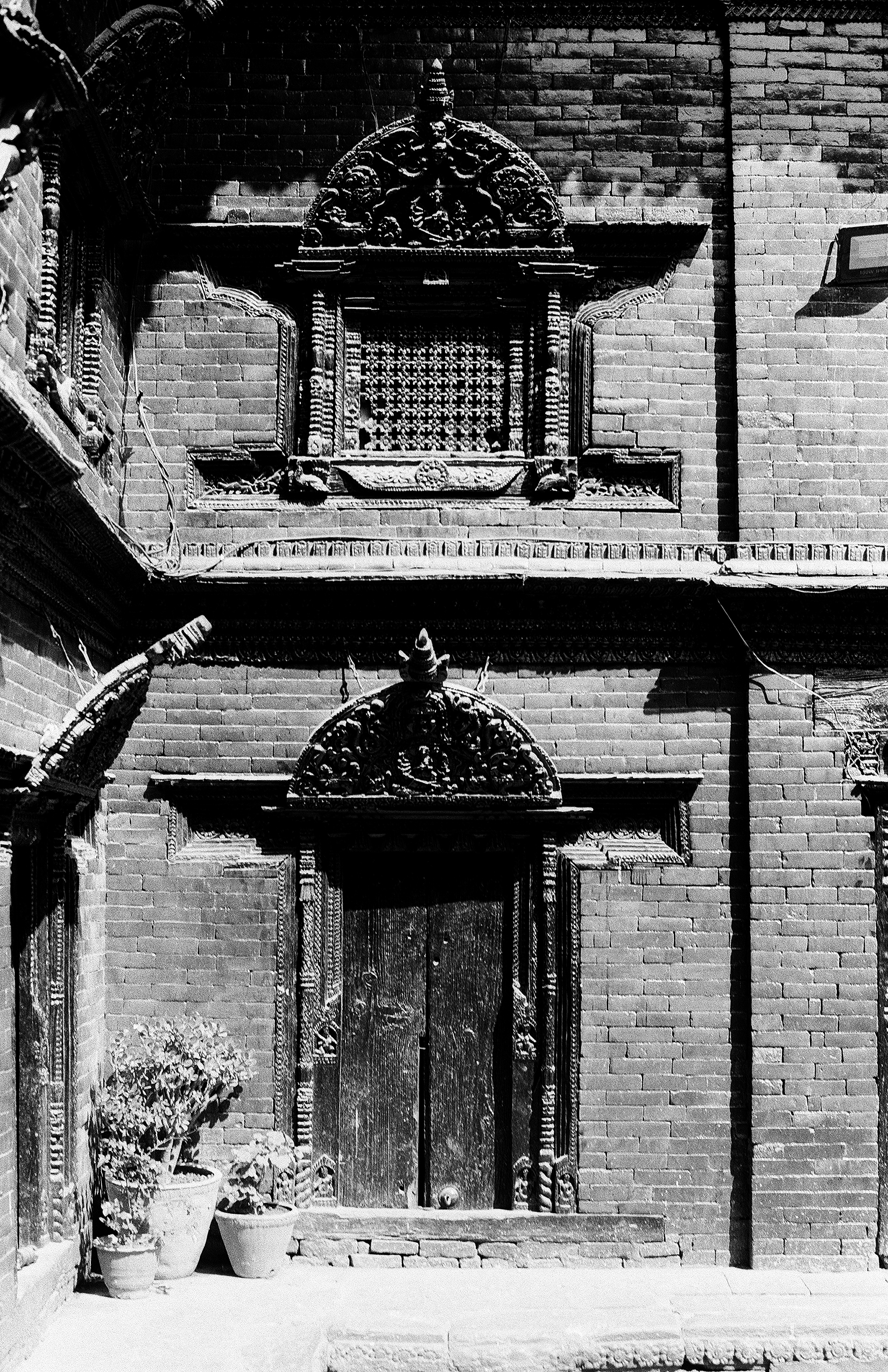 Two-story traditional Newari architecture with ornate wooden windows and carved details