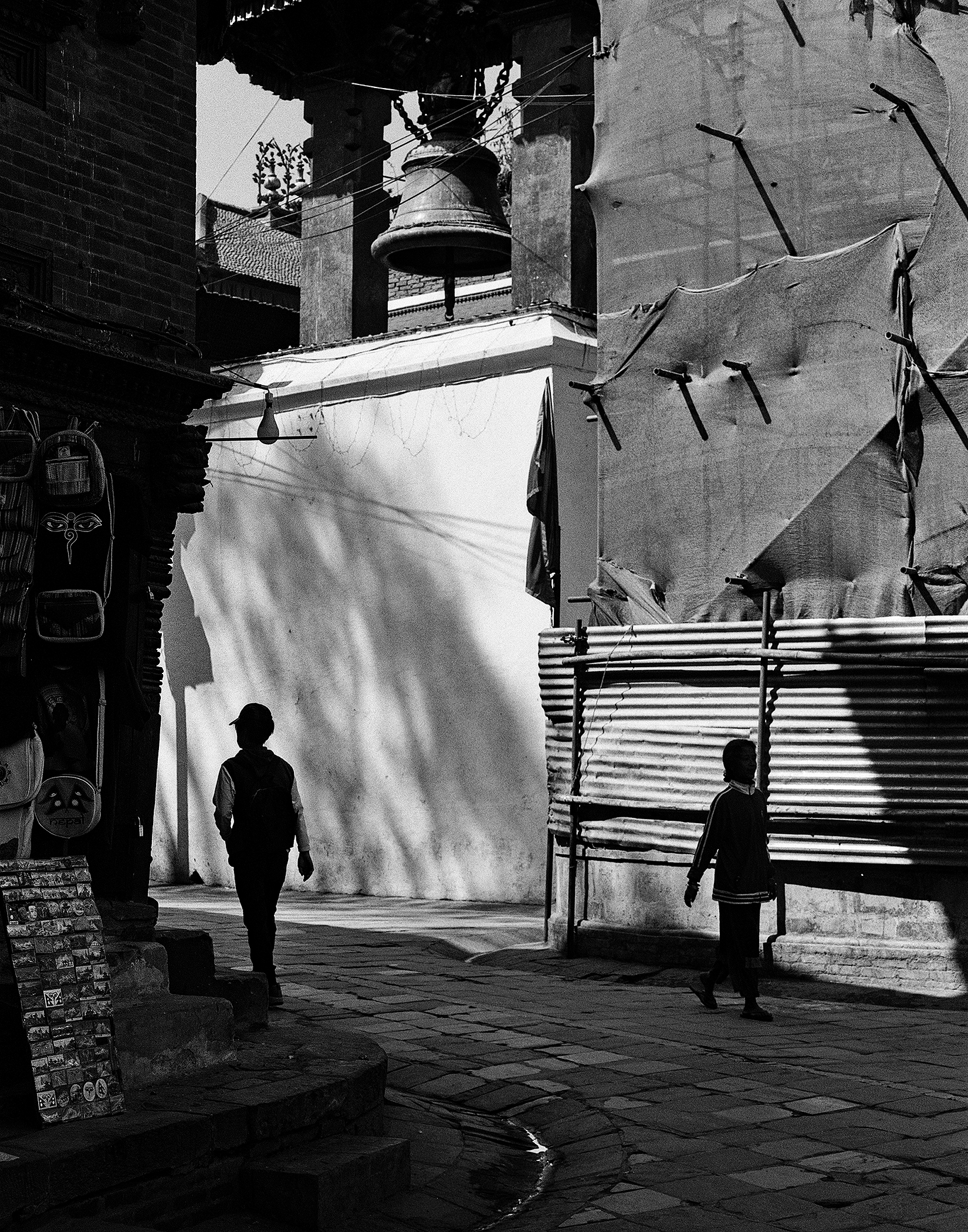 Temple courtyard with cloth draping bell and figures walking through sacred space