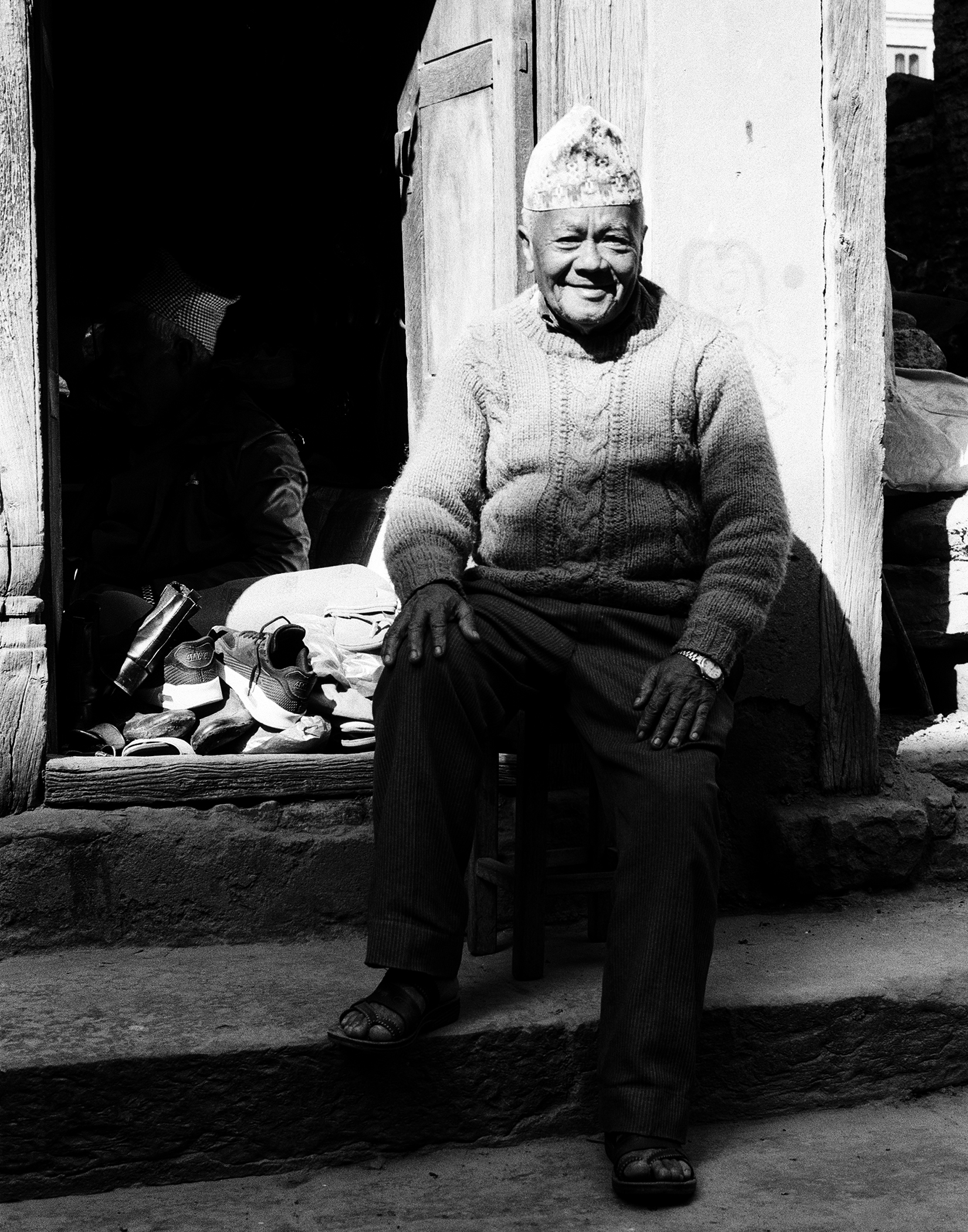 Elderly Nepali woman wearing embroidered traditional clothing and distinctive cultural headwear