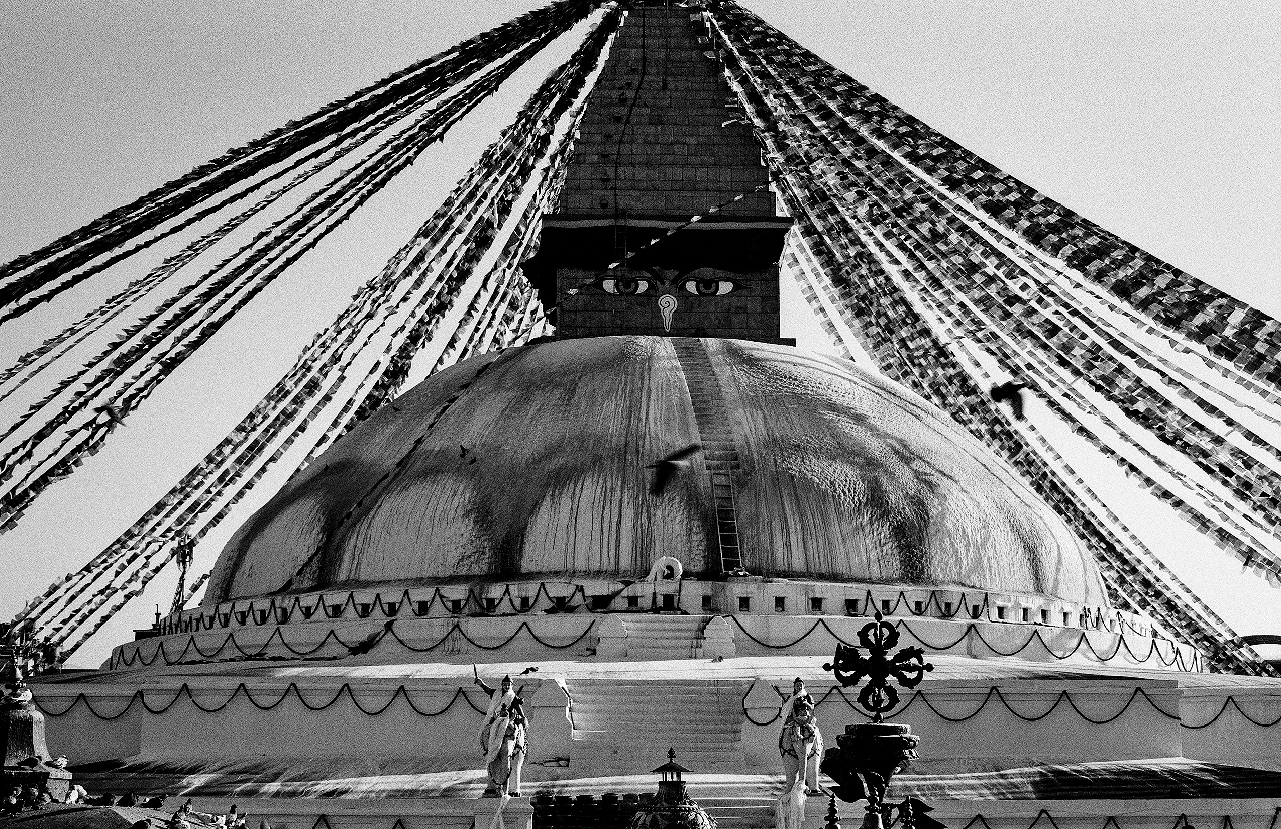 Boudhanath Stupa photographed from below showing massive dome, prayer flags and all-seeing eyes
