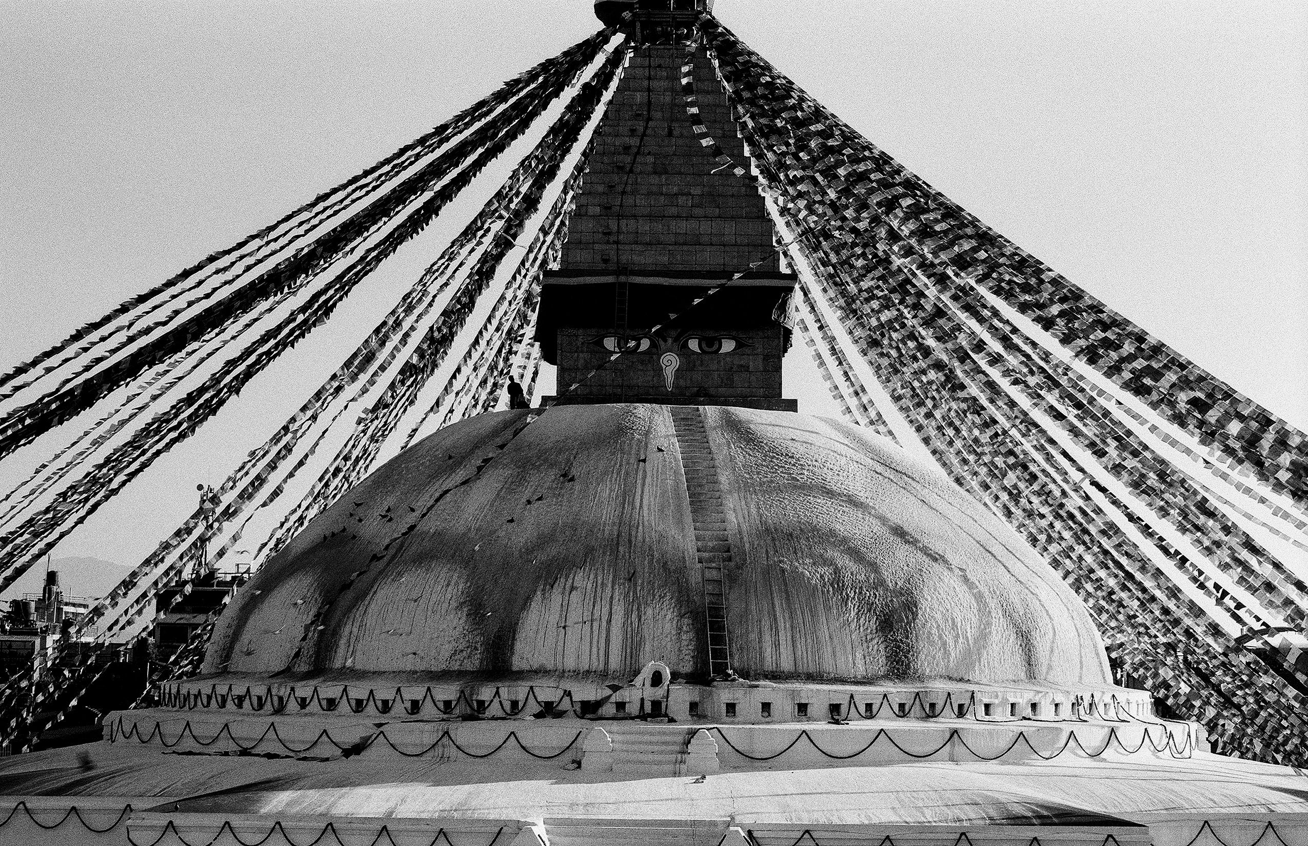 Looking upward at massive dome of Boudhanath Stupa with radiating prayer flags