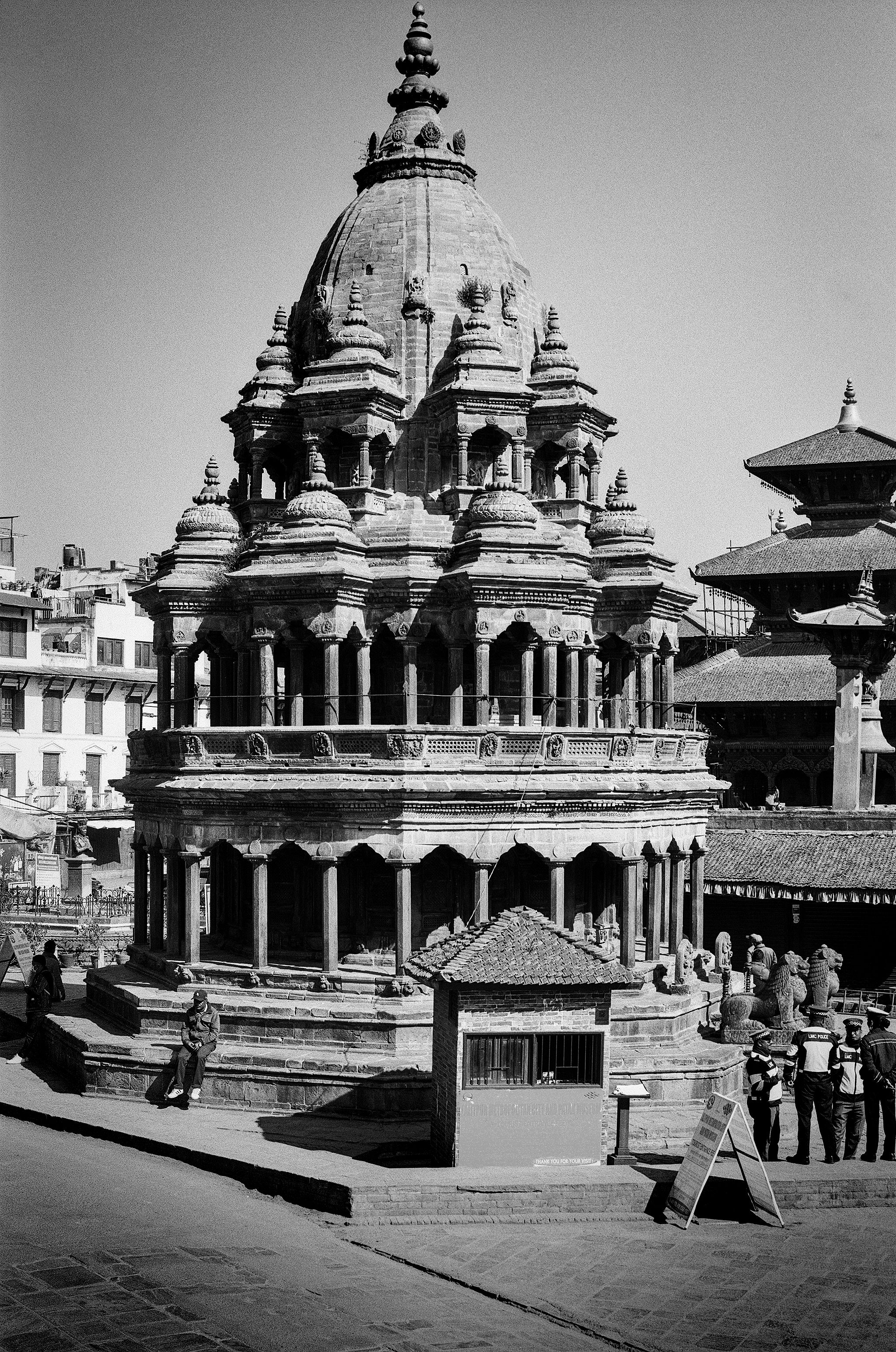 Multi-story Hindu temple with ornate dome and tall spire in traditional Newari architectural style