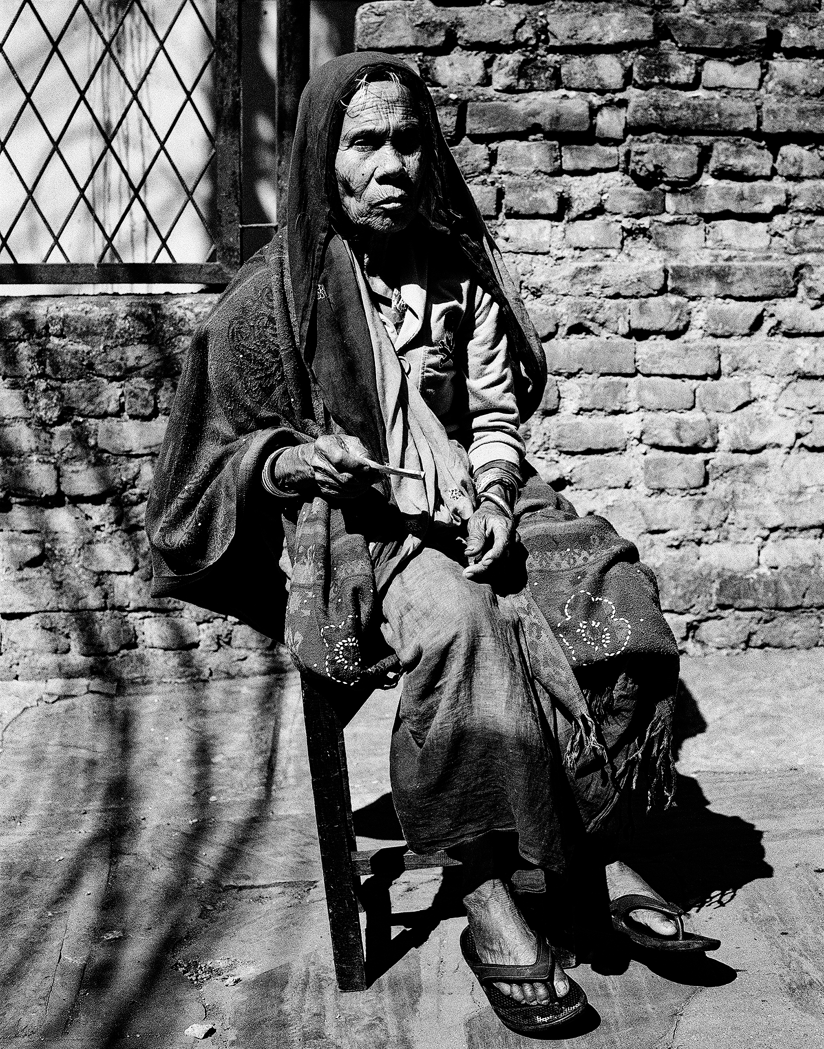 Elderly woman in traditional clothing sitting with household items and daily goods