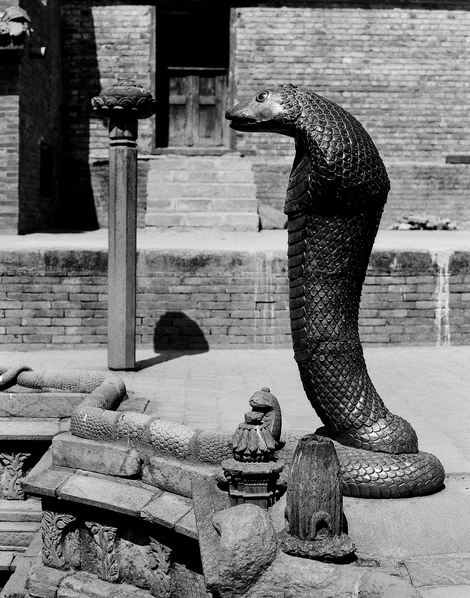 Ornate bronze serpent or naga sculpture with detailed scaled texture and carved base