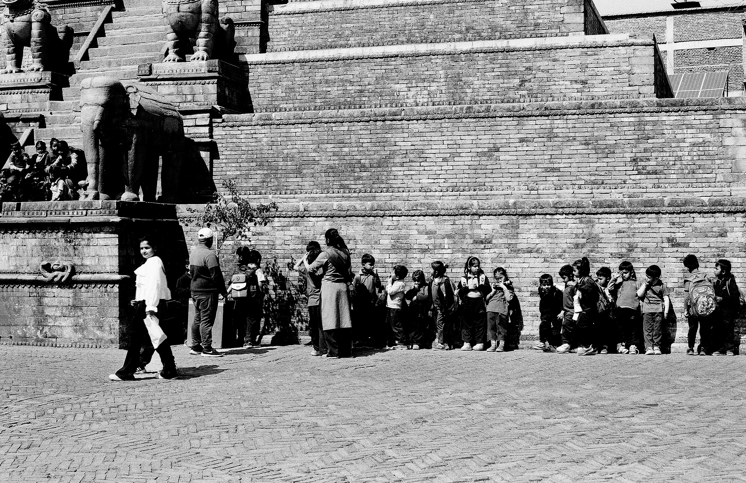 Crowd of visitors gathered at base of Durbar Square temple with protective stone lion guardians