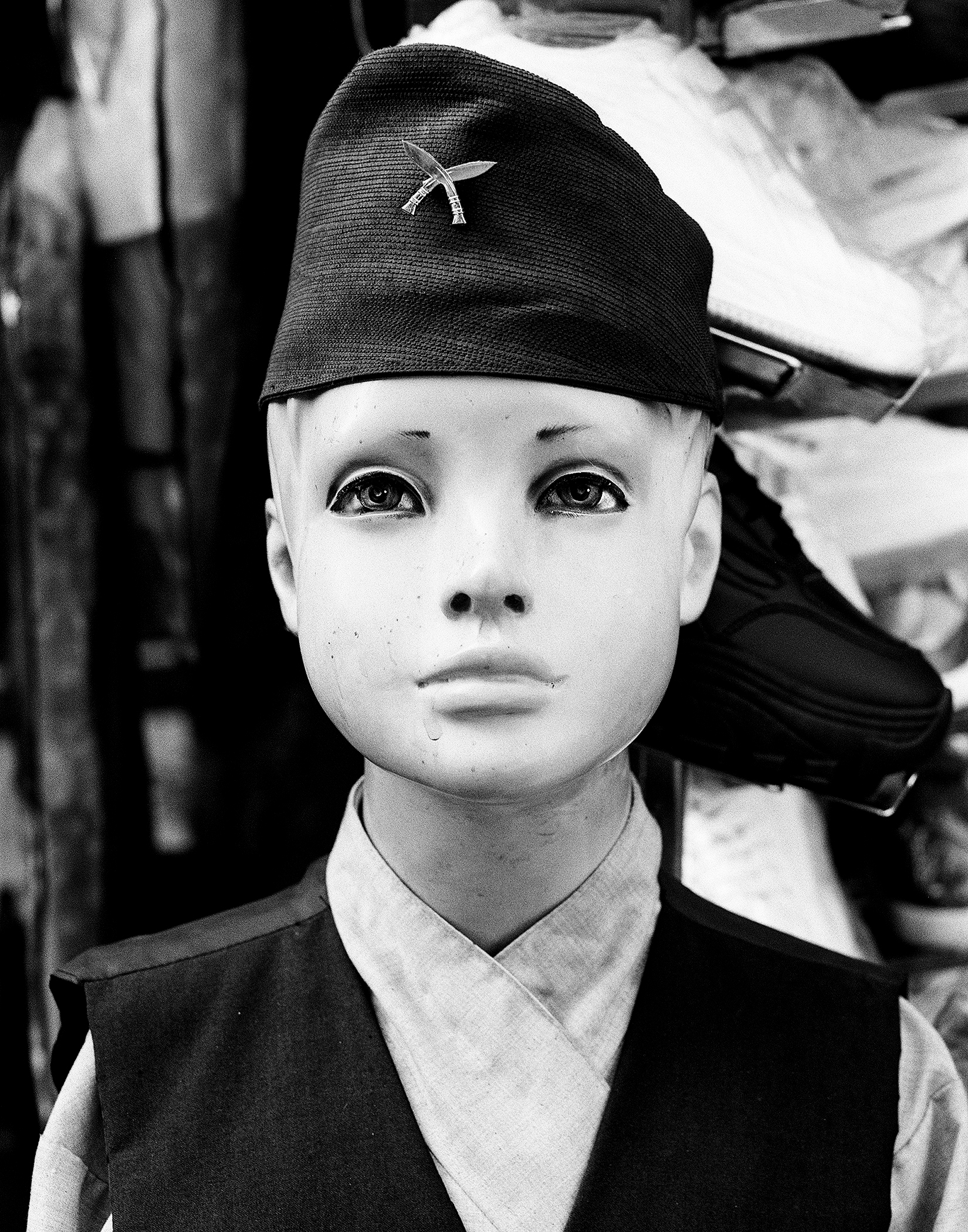 Child wearing traditional black Nepali cap with decorative silver metal ornament pinned on front